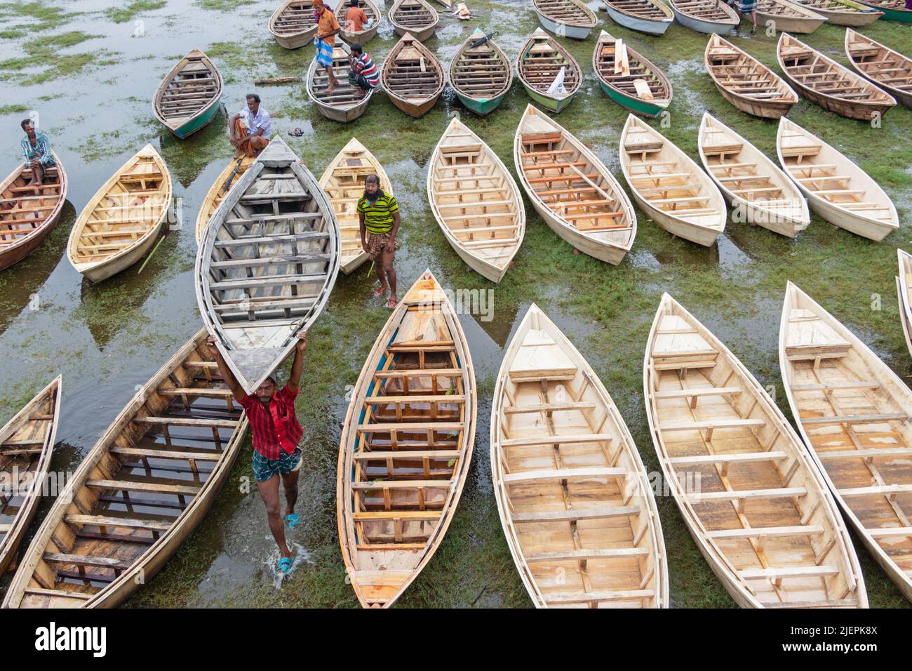 Manikganj, Dhaka, Bangladesch. 28.. Juni 2022. Hunderte von handgefertigten Holzbooten stehen auf dem größten Bootsmarkt von Bangladesch in Manikgonj, Bangladesch, zum Verkauf. Die Menschen strömten auf den Freiluftmarkt, um Boote zu kaufen, um sich auf die kommende Regenzeit vorzubereiten. Bangladesch, bekannt als „Ground Zero for Climate change“, ist mit zusätzlichem Stress konfrontiert, da fast 75 % von Bangladesch unter dem Meeresspiegel liegen und jährlich mit Überschwemmungen konfrontiert sind. Wird von den Einheimischen während des Monsuns verwendet, wenn starke Regenfälle das Flussufer zum Platzen bringen und nahe gelegene Städte und Dörfer untertauchen, kostet jedes Schiff zwischen Â£30 und Â£80 je nach Bedarf Stockfoto