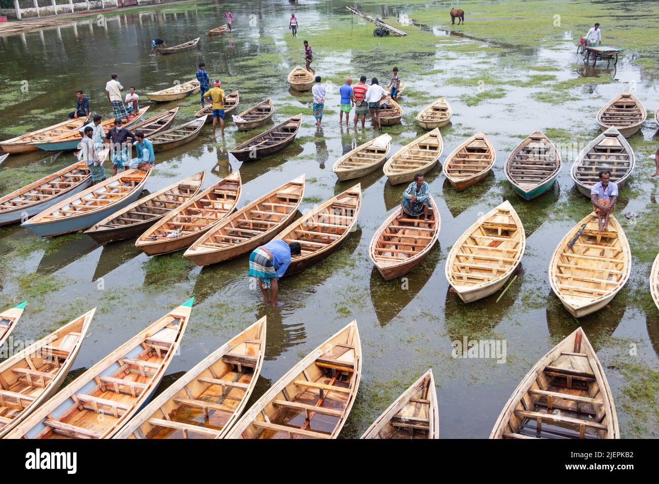 Manikganj, Dhaka, Bangladesch. 28.. Juni 2022. Hunderte von handgefertigten Holzbooten stehen auf dem größten Bootsmarkt von Bangladesch in Manikgonj, Bangladesch, zum Verkauf. Die Menschen strömten auf den Freiluftmarkt, um Boote zu kaufen, um sich auf die kommende Regenzeit vorzubereiten. Bangladesch, bekannt als „Ground Zero for Climate change“, ist mit zusätzlichem Stress konfrontiert, da fast 75 % von Bangladesch unter dem Meeresspiegel liegen und jährlich mit Überschwemmungen konfrontiert sind. Wird von den Einheimischen während des Monsuns verwendet, wenn starke Regenfälle das Flussufer zum Platzen bringen und nahe gelegene Städte und Dörfer untertauchen, kostet jedes Schiff zwischen Â£30 und Â£80 je nach Bedarf Stockfoto