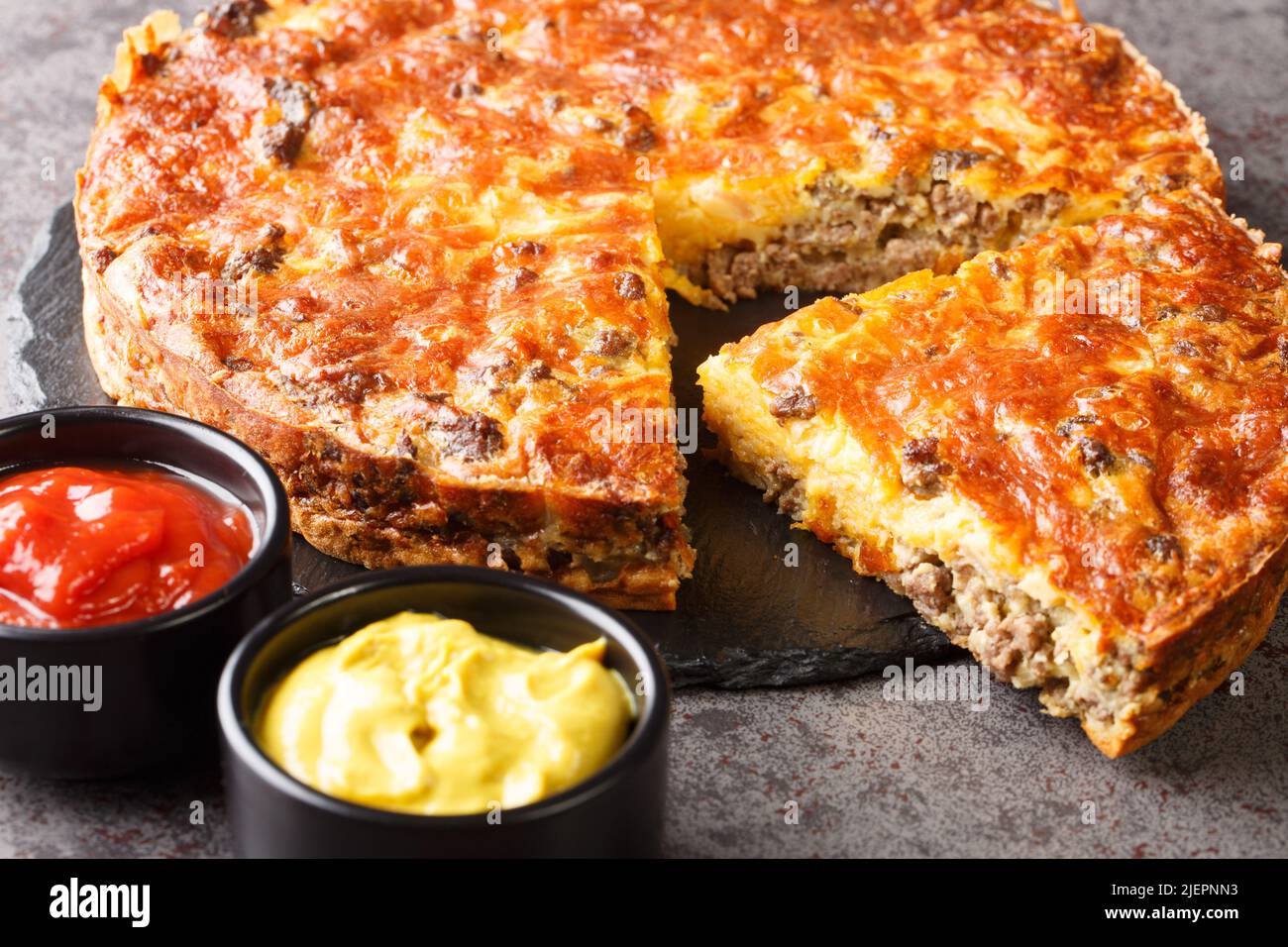 Cheeseburger-Pastete aus Rind, serviert mit Saucen aus nächster Nähe auf einem Schieferbrett auf dem Tisch. Horizontal Stockfoto