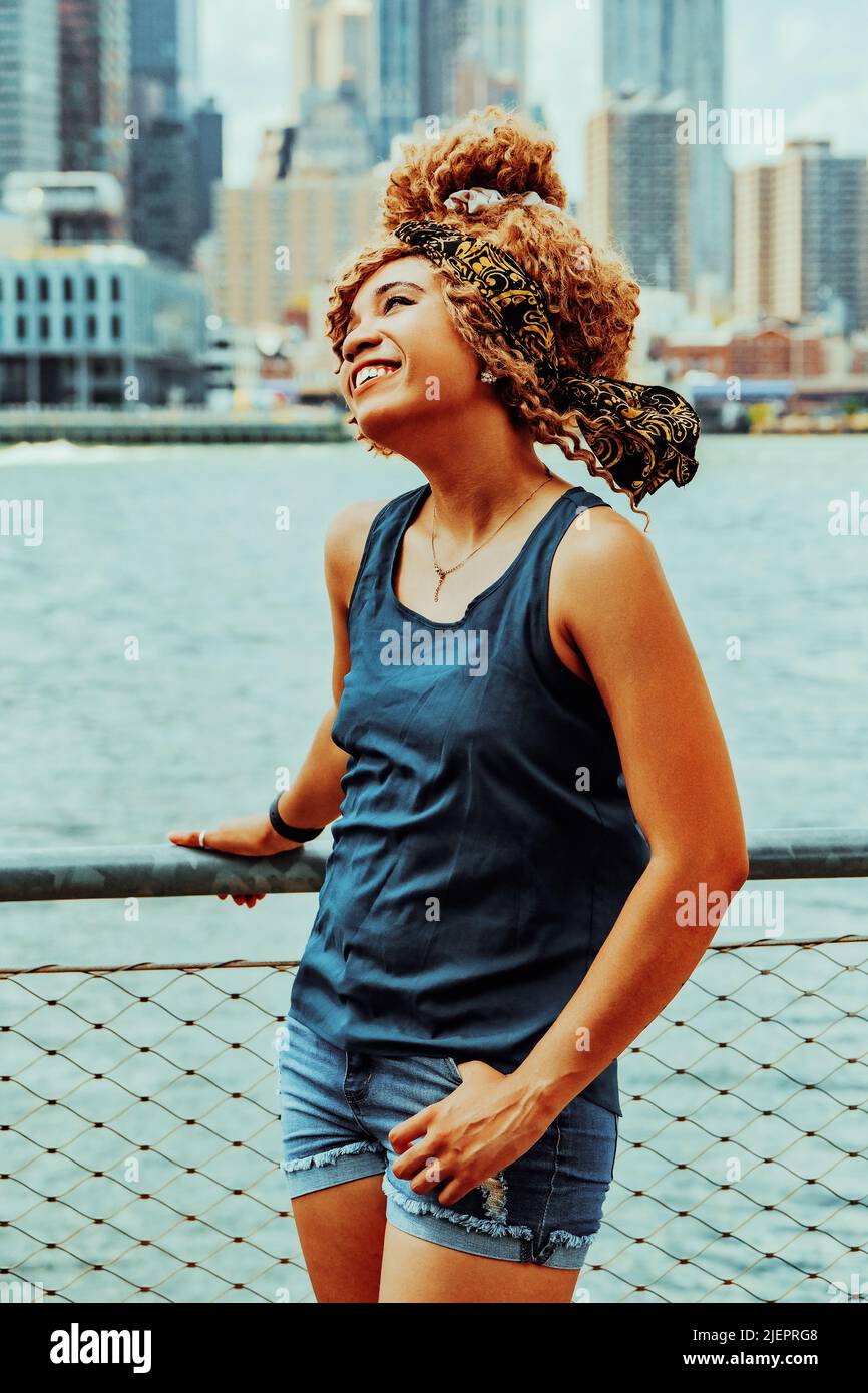 Portrait schöne junge Erwachsene Frau Afro Frisur mit Manhattan New York City Skyline im Hintergrund Außenaufnahme Stockfoto