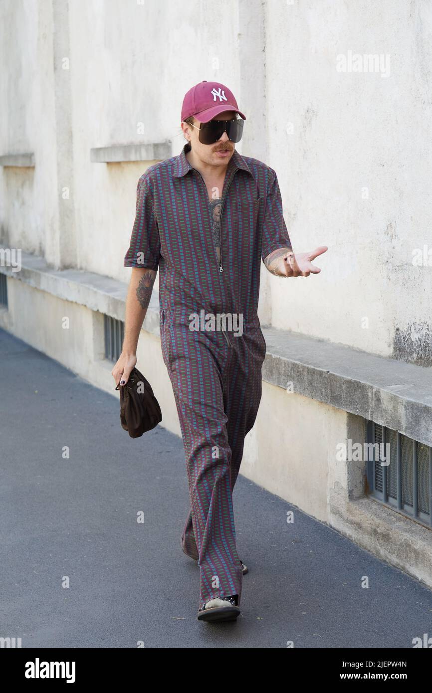 MAILAND, ITALIEN - 19. JUNI 2022: Mann mit braunen und blauen Overalls und burgunderfarbener Mütze vor der Prada Fashion Show, Mailand Fashion Week Street Style Stockfoto