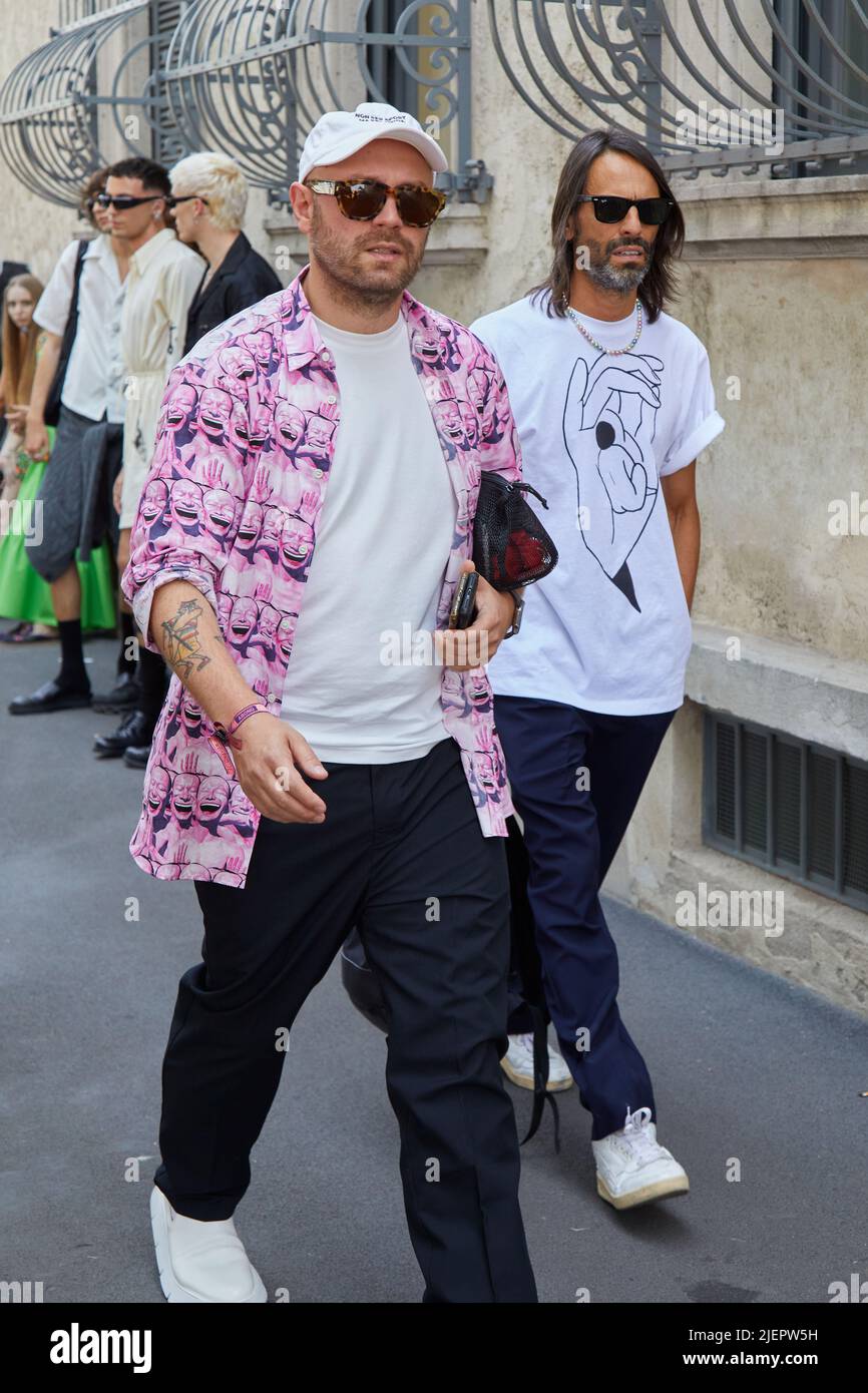 MAILAND, ITALIEN - 19. JUNI 2022: Männer mit rosa Hemd mit lächelnden Designs und schwarzen Hosen vor der Prada Fashion Show, Mailand Fashion Week Street Style Stockfoto