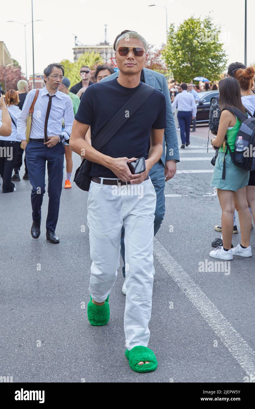 MAILAND, ITALIEN - 19. JUNI 2022: Weiße Männerhose, schwarzes T-Shirt und grüne Hausschuhe vor der Prada Fashion Show, Mailand Fashion Week Street Style Stockfoto