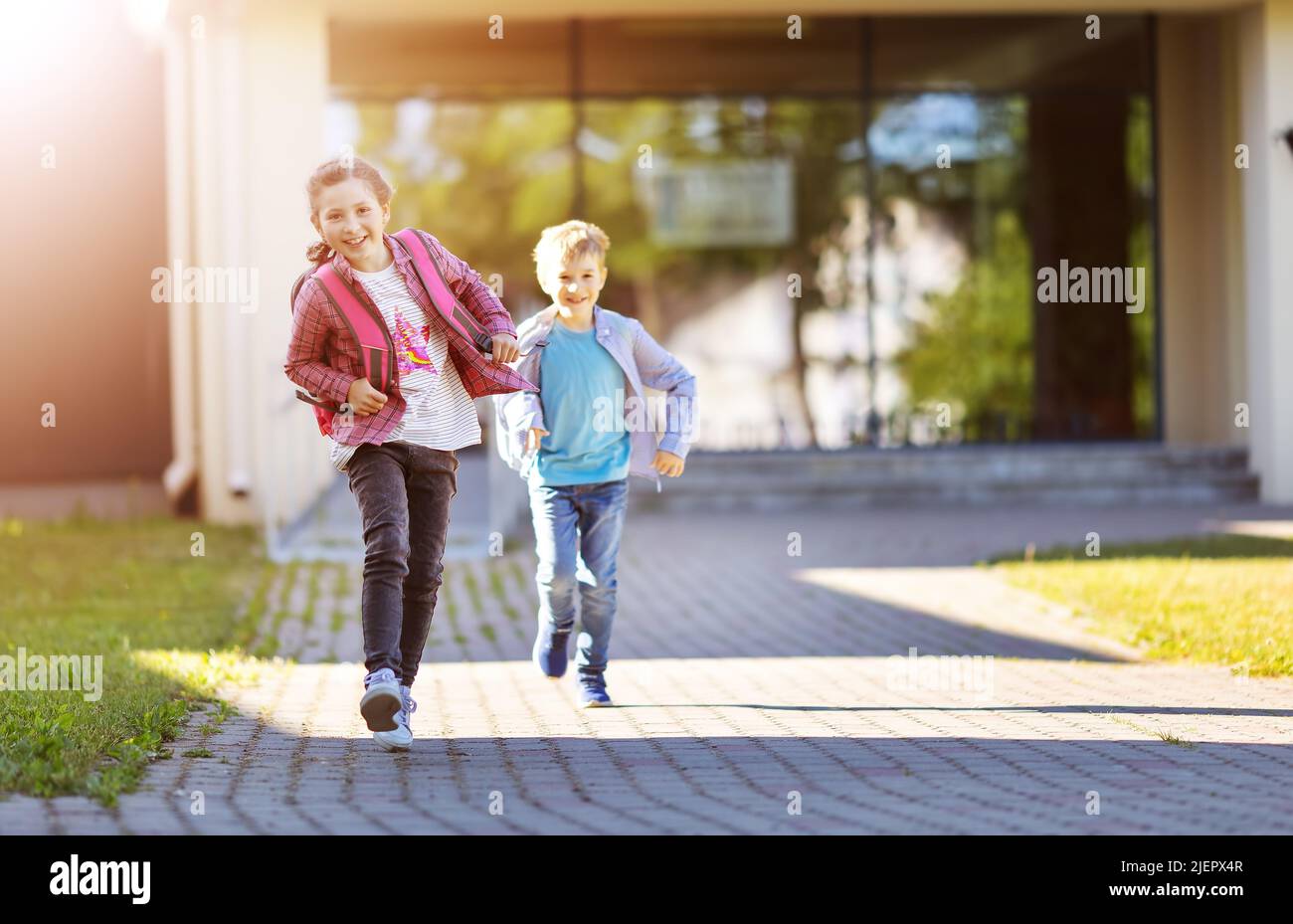 Mädchen und Jungen, die nach dem Studium von der Schule laufen. Stockfoto