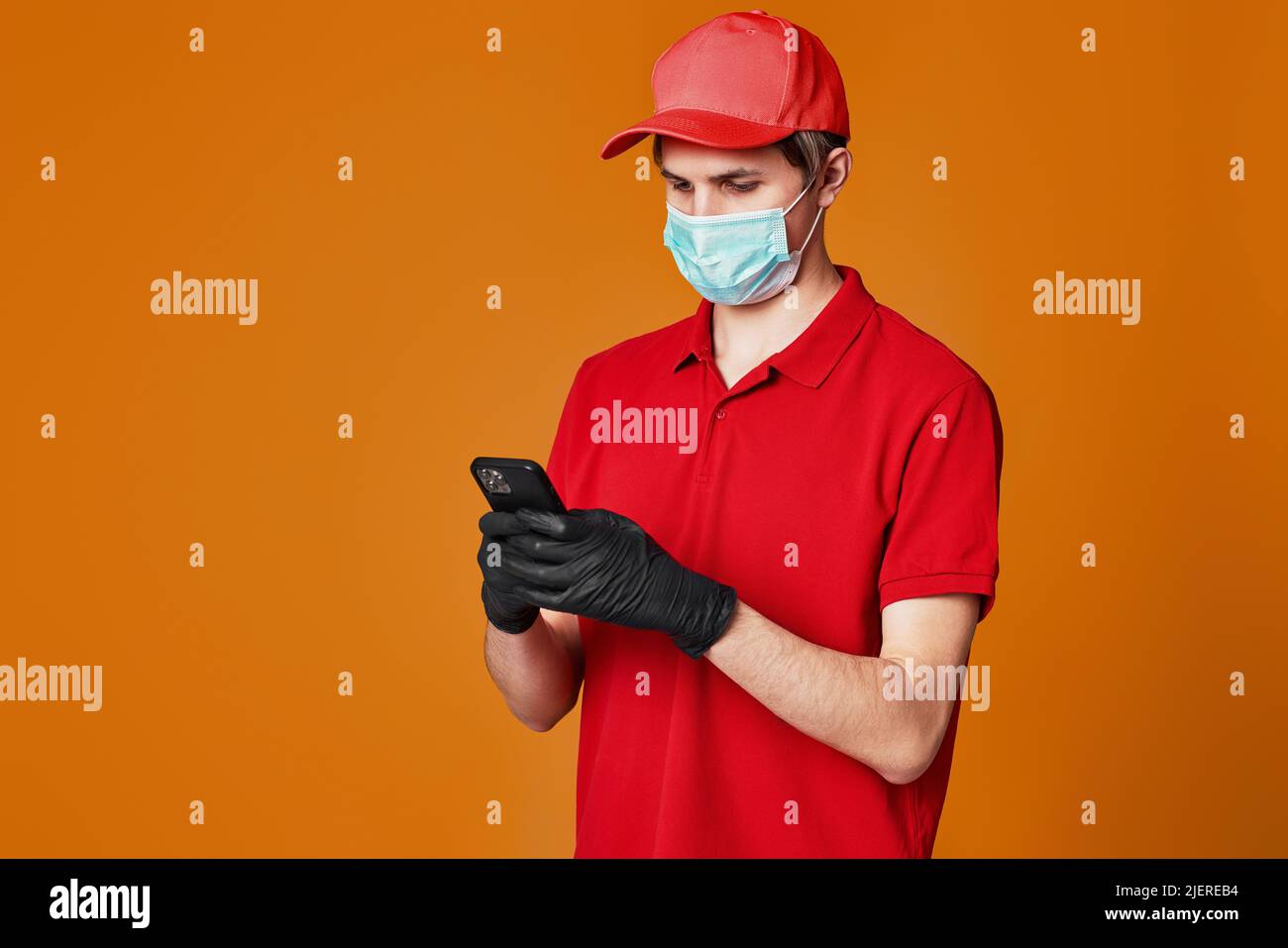 Angestellter in roter Kappe Gesichtsmaske, leerer Pappkarton Stockfoto