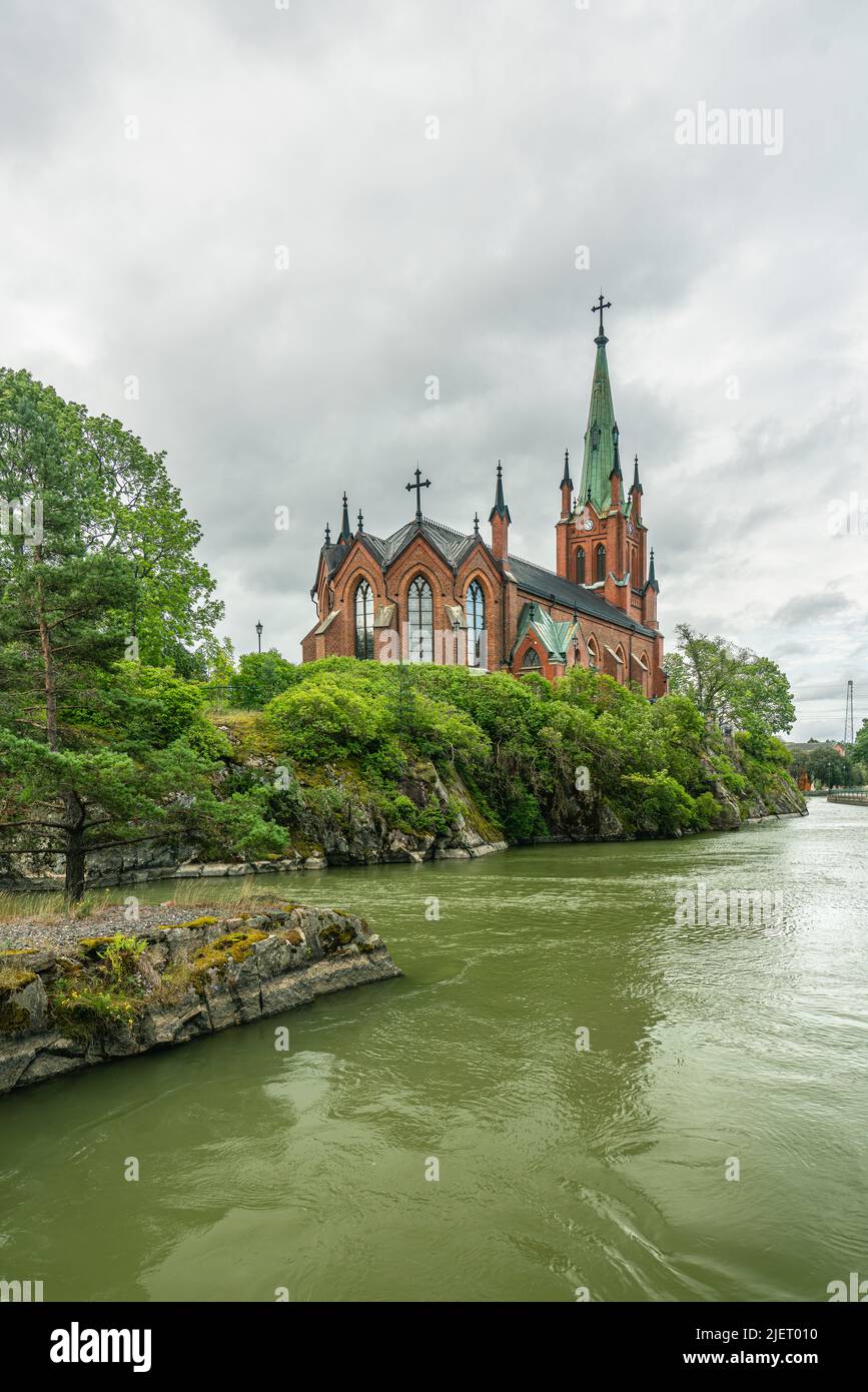 Schöne Kirche an einem Sommertag in Trollhattan, Schweden mit einem Fluss vor dem Ufer, der Teil eines Kanals ist.1857 am 7.. august wurde Trollhättan Stockfoto