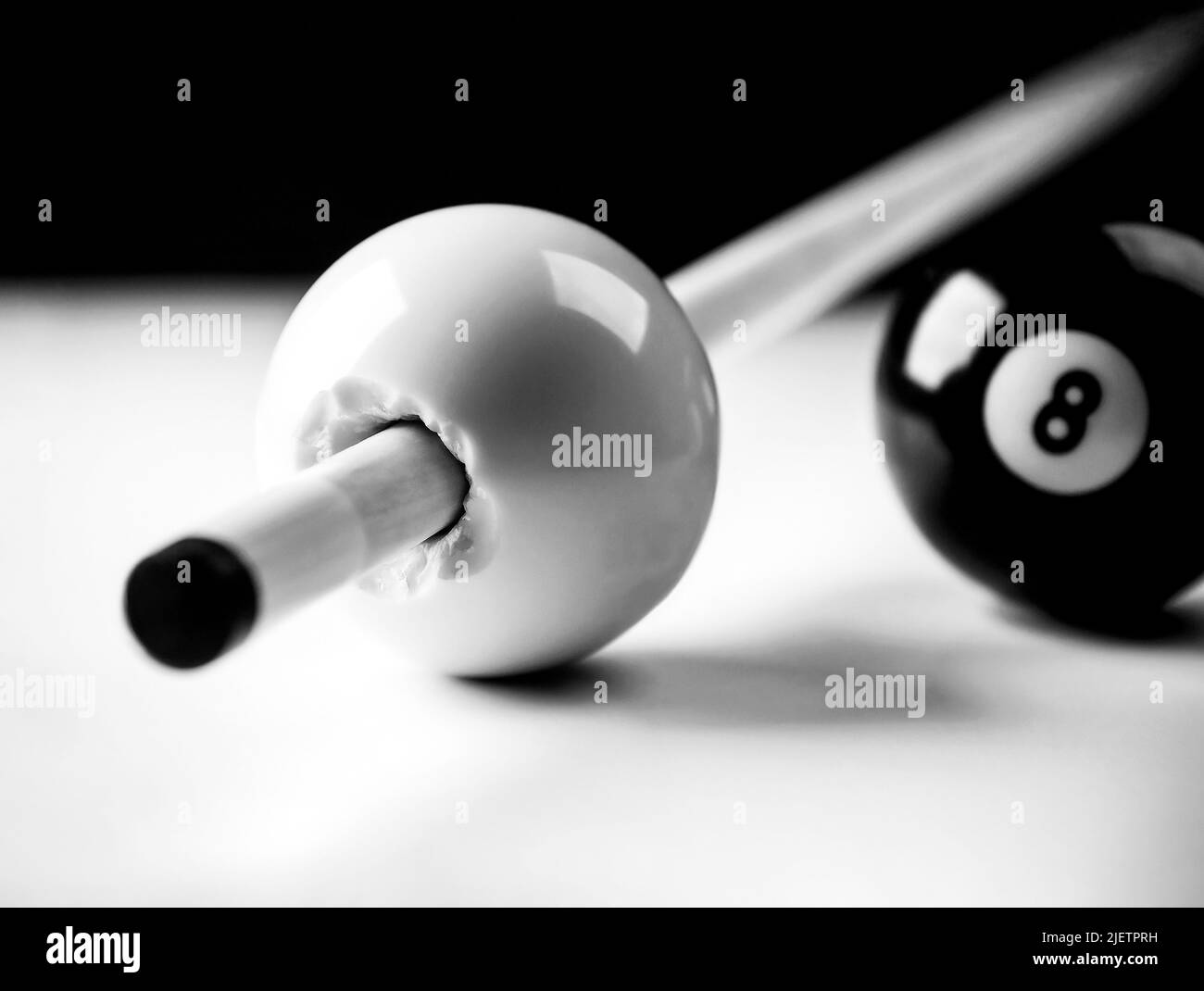 Queue-Stick bricht durch einen Cueball mit acht Ball im Hintergrund, realistische Fotografie Stockfoto