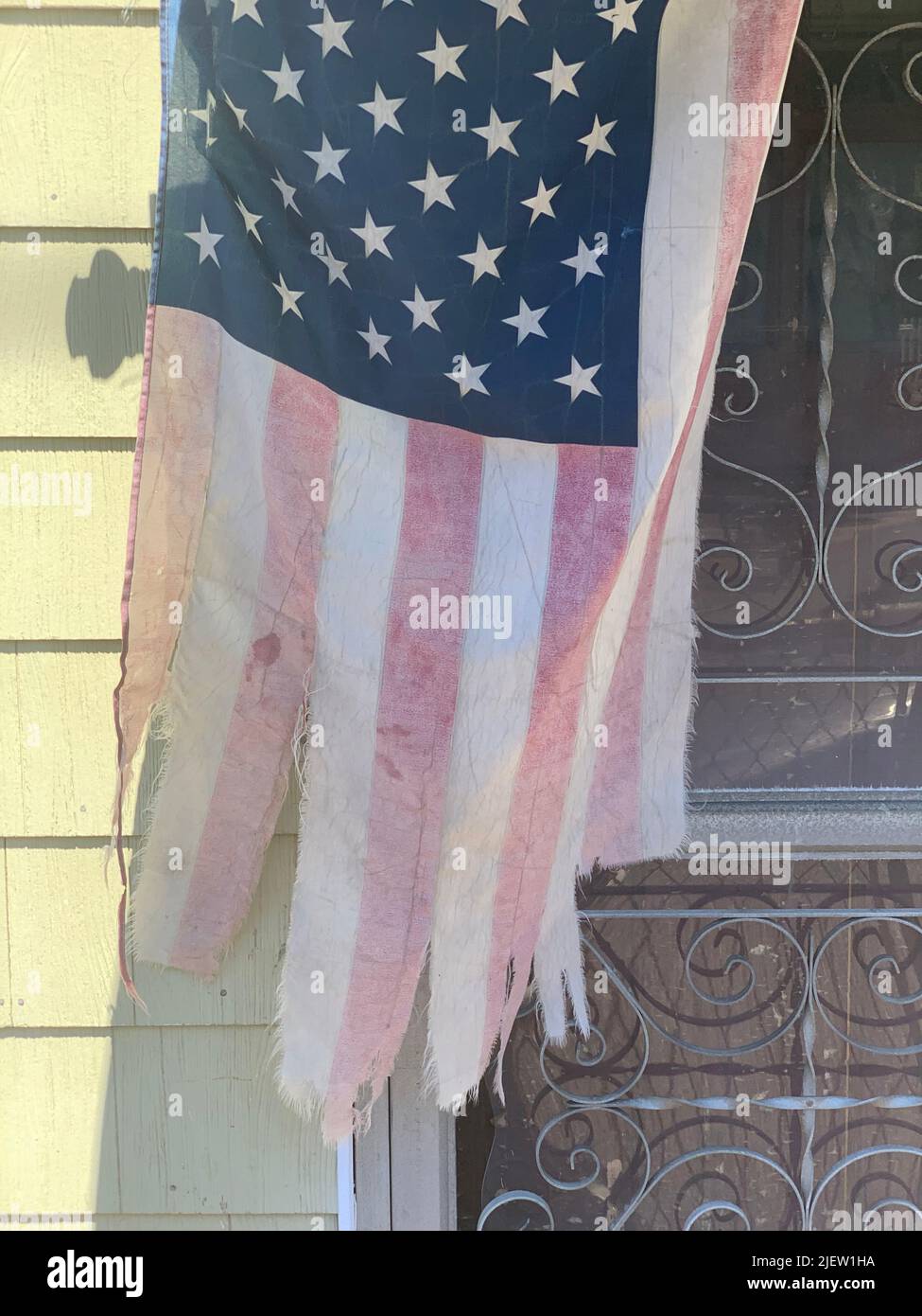 Eine zerfetzte amerikanische Flagge baumelt vor einem vernachlässigten Grundstück Stockfoto