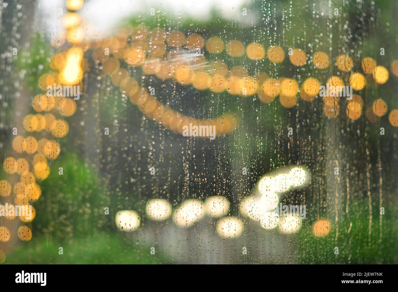 Regentropfen im Fenster und Bokeh von Lichtern am Hochzeitstag im Sommer Stockfoto
