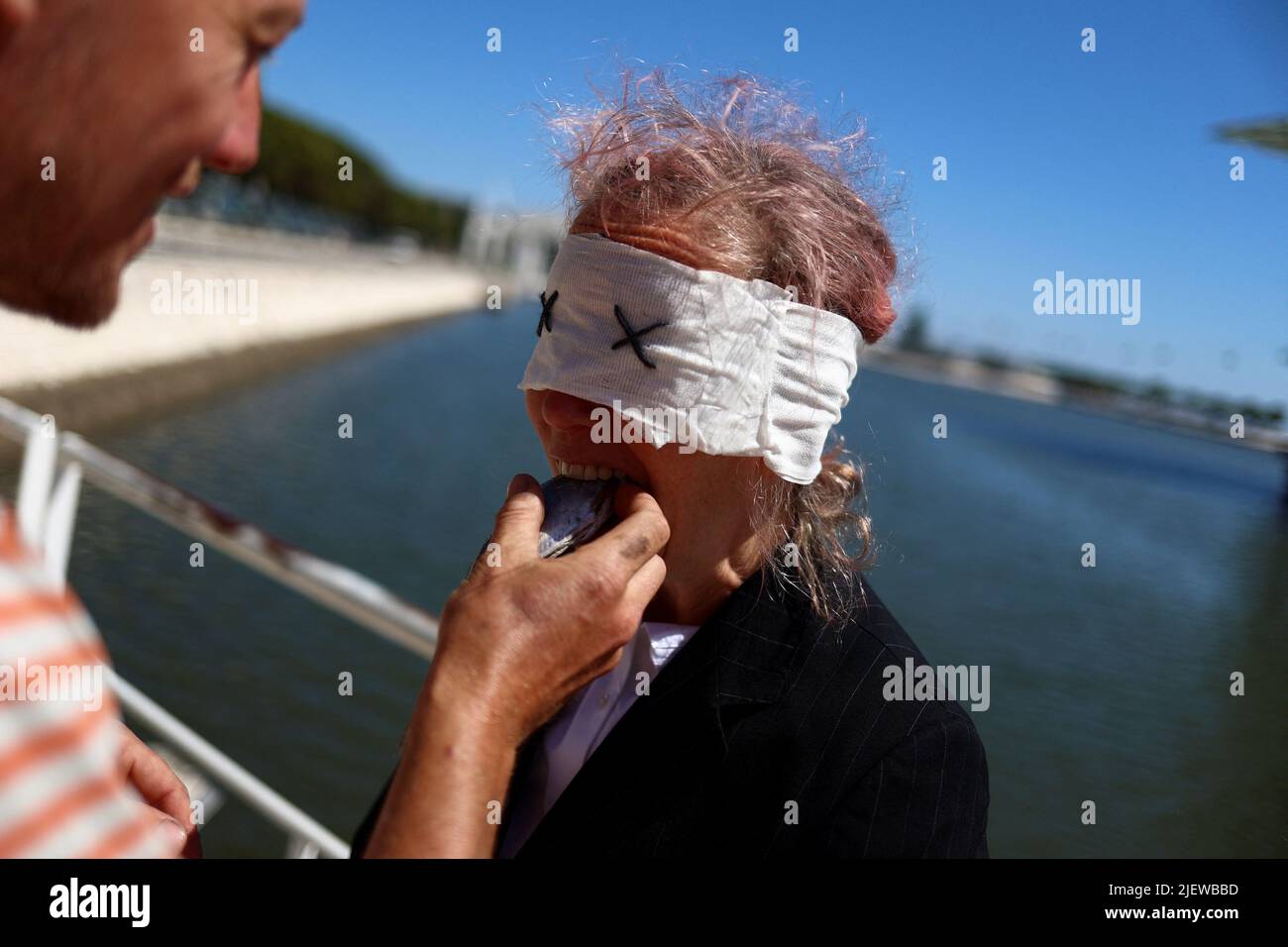 Eine Protesterin bringt ihr eine Makrele in den Mund, während sie an einem Protest vor der UN-Ozeankonferenz teilnimmt, um die Mitgliedsstaaten zu fordern, einen Vertrag zum Schutz der Hohen See in Lissabon, Portugal, am 28. Juni 2022, abzuschließen. REUTERS/Pedro Nunes Stockfoto