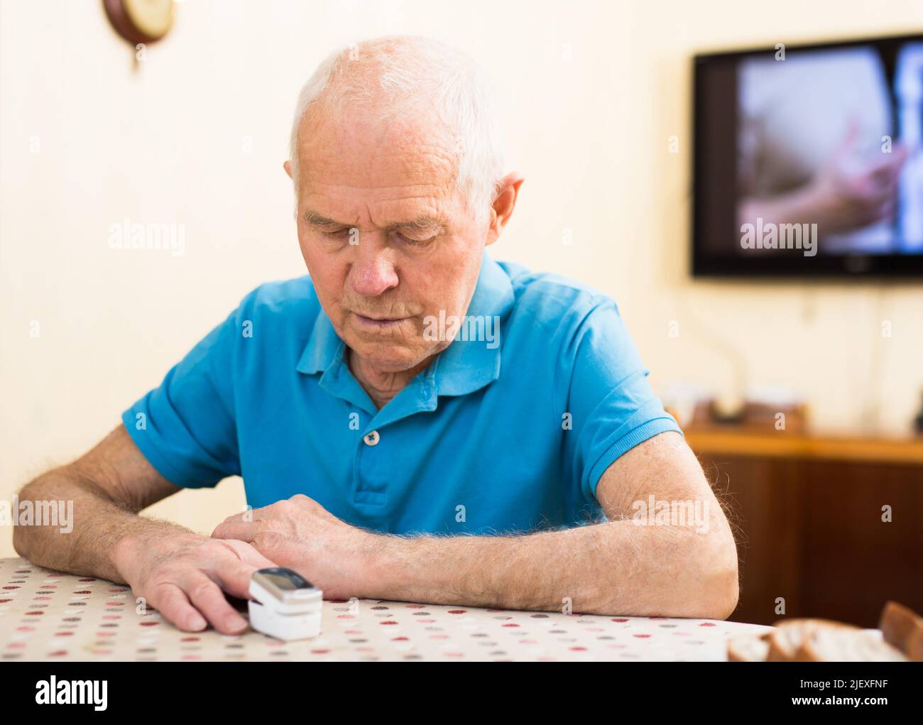 Besorgter älterer Mann, der sich zu Hause die Sauerstoffsättigung misst Stockfoto