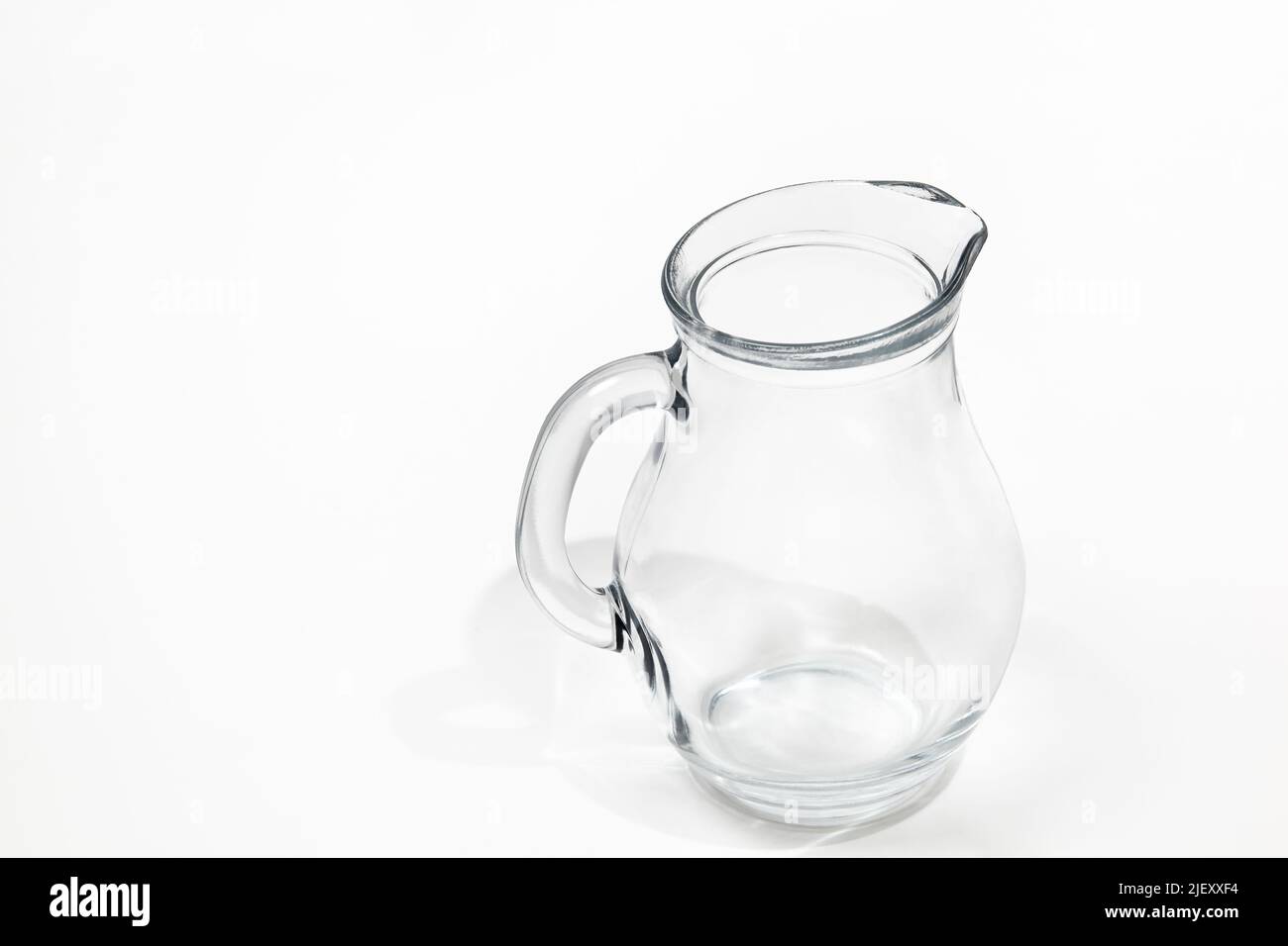 Wasserkanne aus Glas auf weißem Hintergrund. Platz für Text, Werbung, Menü und gedruckte Materialien Stockfoto