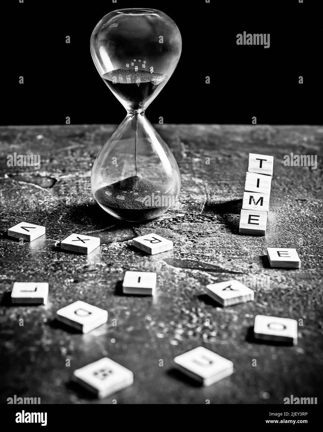 Eine Sanduhr mit schwarzem Sand und dem Wort 'Zeit', in schwarz und weiß Stockfoto