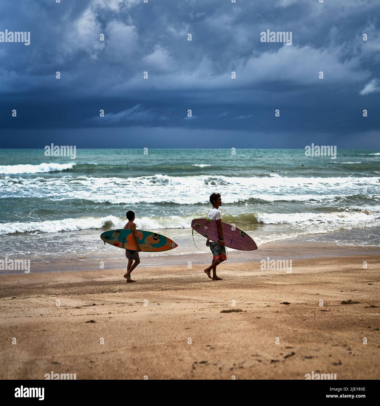 Vater und Sohn tragen ihre Surfbretter an einem Strand in Thailand Stockfoto