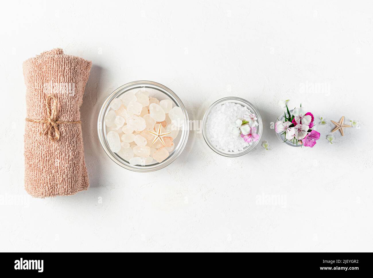Handtuch, Meersalz und Blumen auf grauem Hintergrund. Stockfoto