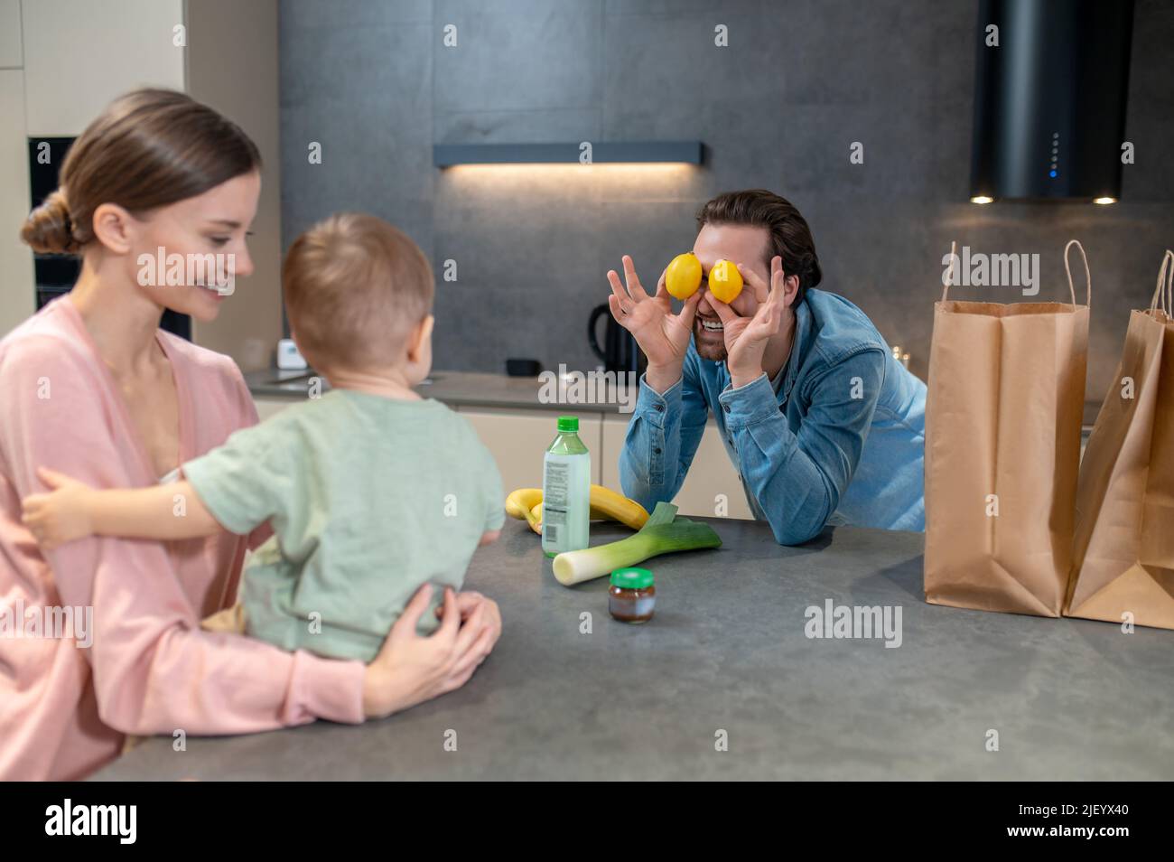 Mama hält ein Baby und Papa bringt ihn zum Lachen Stockfoto