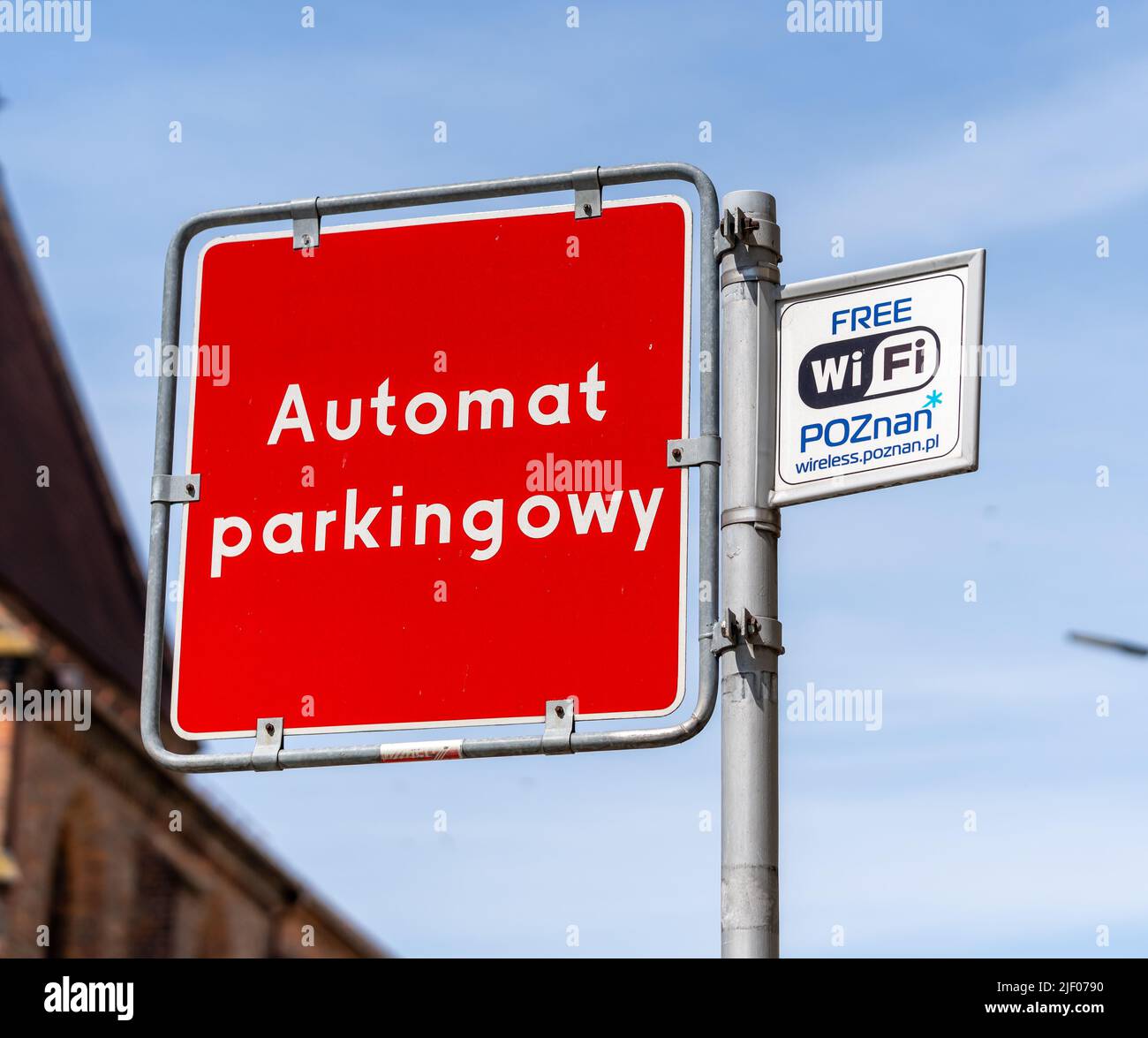 Ein roter automatischer Parkplatz und kostenlose WiFi-Schilder auf einem Pfosten gegen einen blauen Himmel im Stadtzentrum Stockfoto