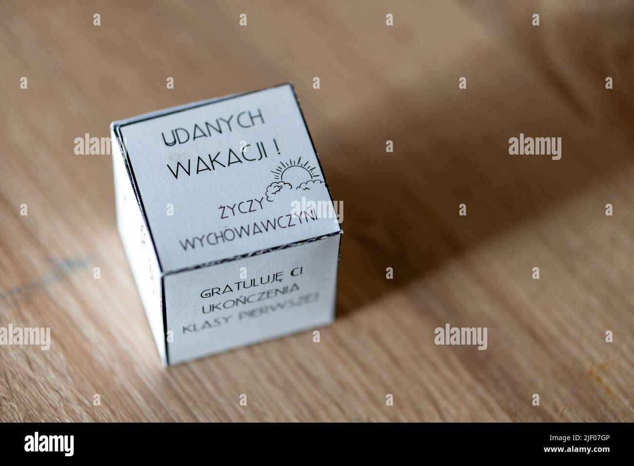 Ein Papierwürfel mit „Happy Vacations“-Text in polnischer Sprache auf einem Holztisch Stockfoto