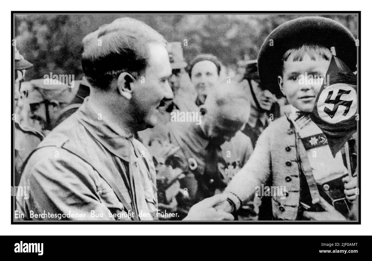 Adolf Hitler in Nazi-SA-Uniform, der die Hand eines bemusten kleinen Jungen hält, der eine Nazi-Swastika-Flagge hält, in typisch bayerischem Kostüm Bavaria Nazi-Deutschland 1930s.die Sturmabteilung (SA) war der ursprüngliche paramilitärische Flügel der NSDAP. Stockfoto