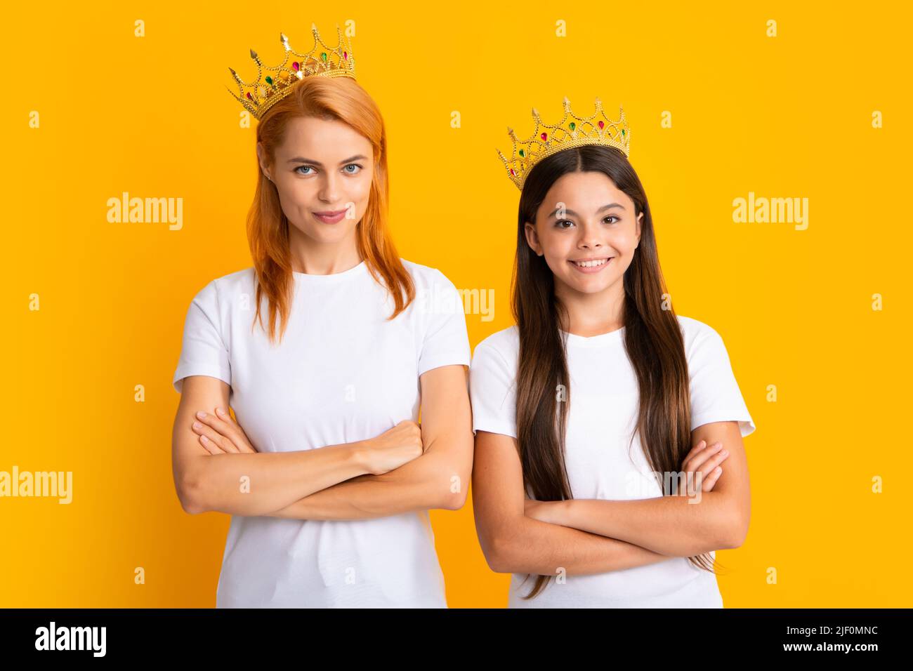 Arrogante Mutter und Tochter Kind mit Kronen auf gelbem Hintergrund, egoistisch. Studio Porträt von teen Prinzessin. Stockfoto