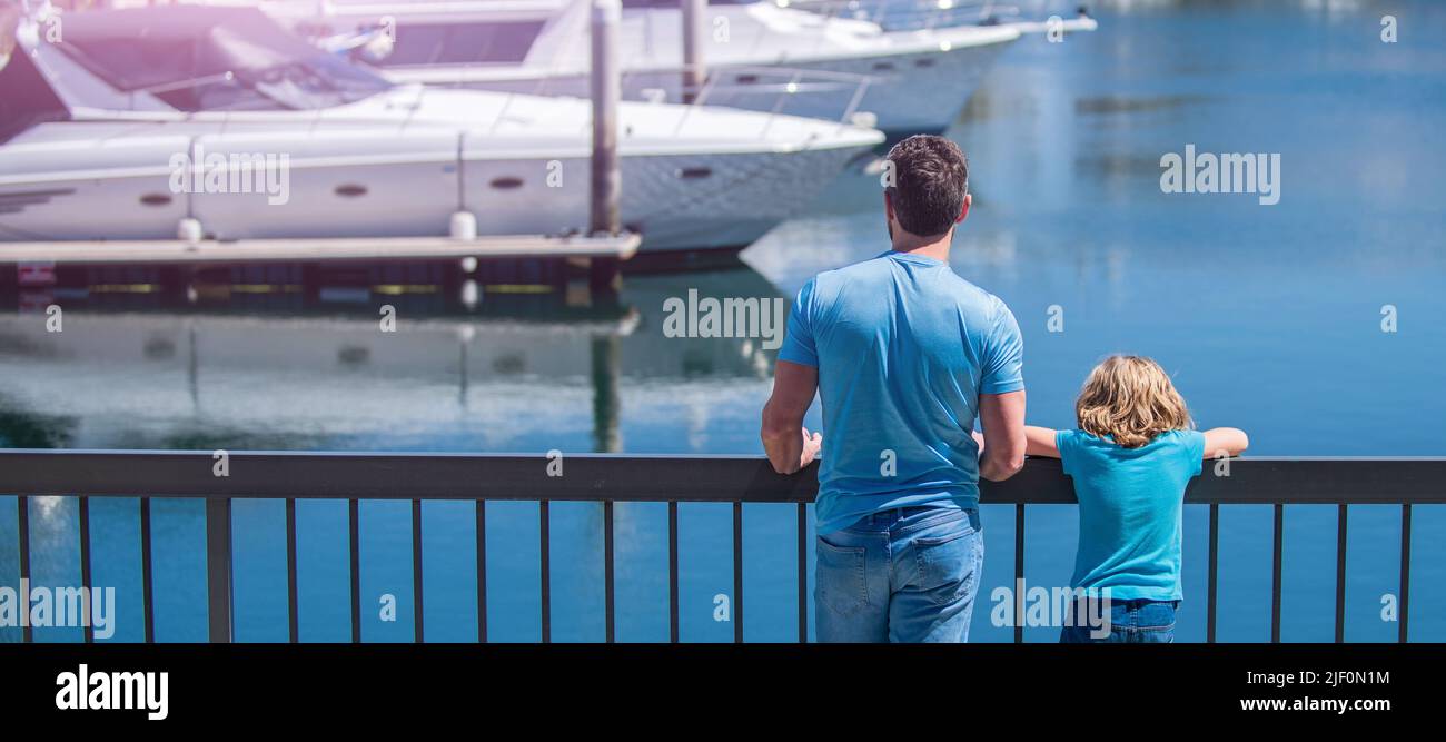Sommerbanner, Elternschaft und Vaterschaft. Vatertag. Vater und Sohn blicken auf Yachten im Hafen. Stockfoto