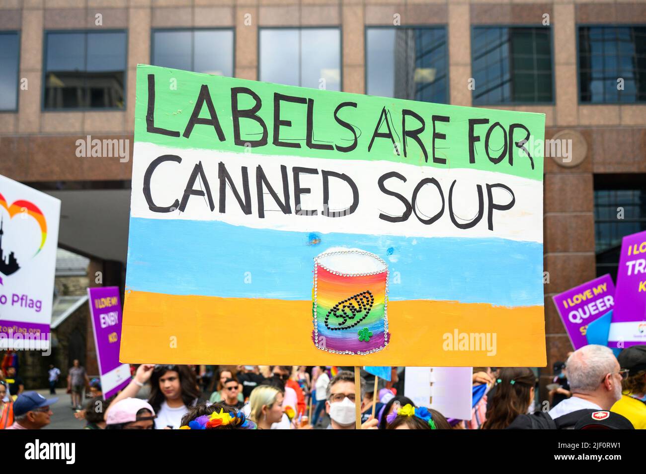 Nahaufnahme eines Schildes mit der Aufschrift „Etiketten sind für Konserven“. Der Text ist unter einer Menschenmenge, die in der Pride Parade marschiert Stockfoto