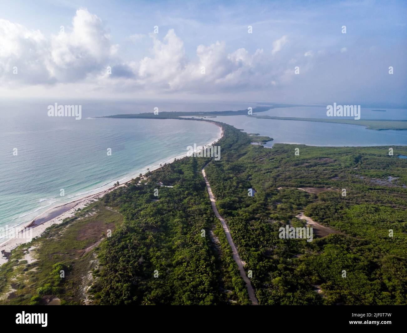 Luftaufnahme der Küstensanddüne des Sian Kaan Nationalparks zwischen dem Karibischen Meer und der Süßwasserlagune mit Strandstraße und Wolkenhimmel während der goldenen Stunde Stockfoto