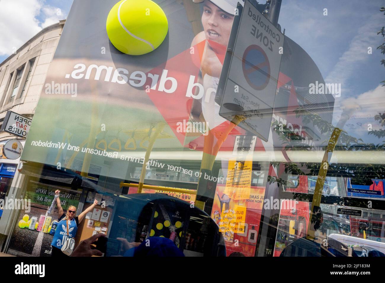 Im Fenster eines Busses spiegelt sich die britische Tennisspielerin Emma Raducanu am zweiten Wettkampftag während der Wimbledon Lawn Tennis Association Championships am 28.. Juni 2022 in London, England, auf einer riesigen Werbetafel im Stadtzentrum von Wimbledon wider. Stockfoto