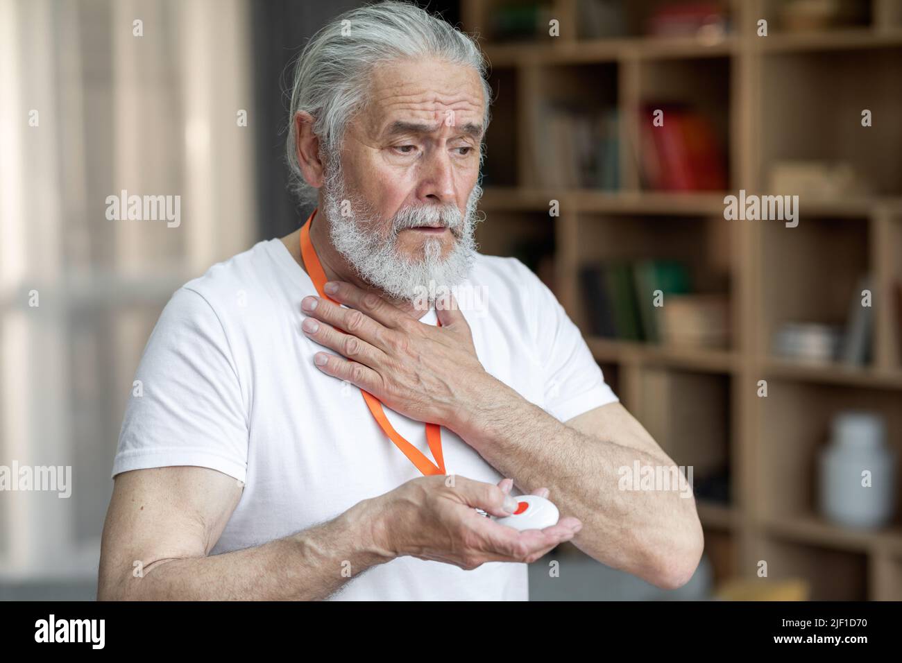 Kranker älterer Mann, der einen Panikknopf auf die Notfallausrüstung drückt Stockfoto