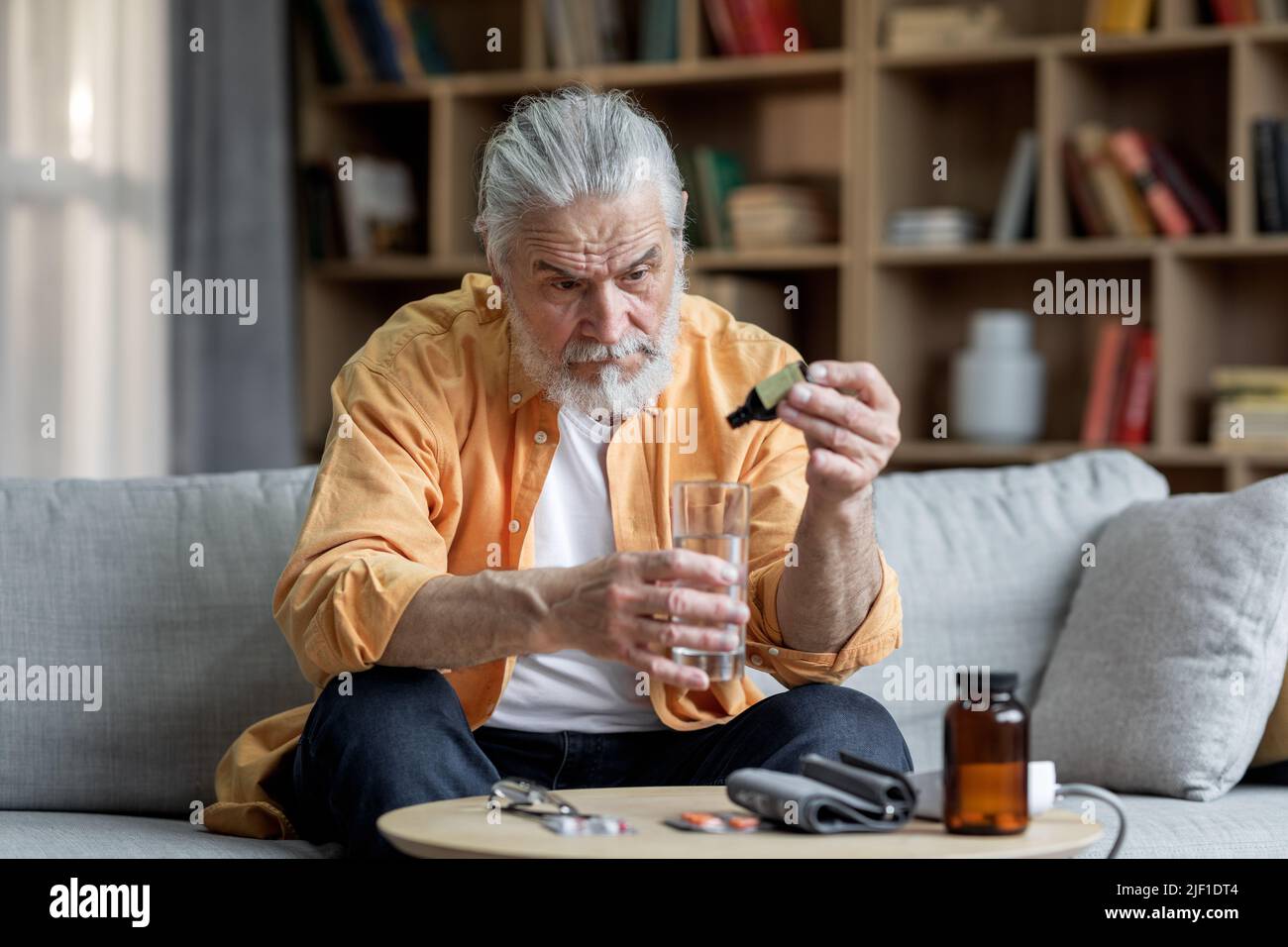 Kranker älterer Mann, der an Bluthochdruck leidet, mit Medikamenten Stockfoto