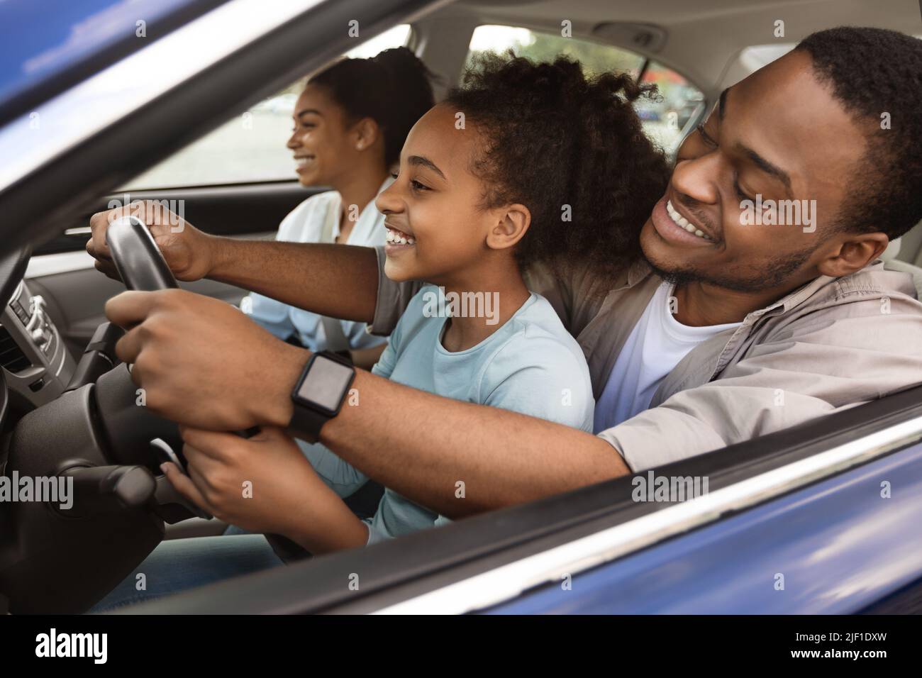 Fröhlich Afrikanisch Amerikanisch Papa Lehre Preteen Tochter Auto Zu Fahren Stockfoto