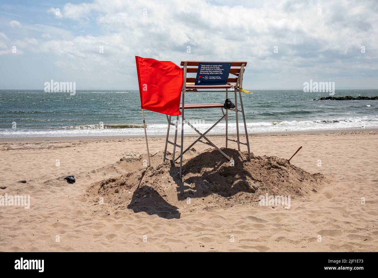 Kein Schwimmen, kein Planschfahren. Rote Flagge durch Rettungsschwimmerstuhl am leeren Coney Island Beach in Brooklyn, New York City, Vereinigte Staaten von Amerika Stockfoto