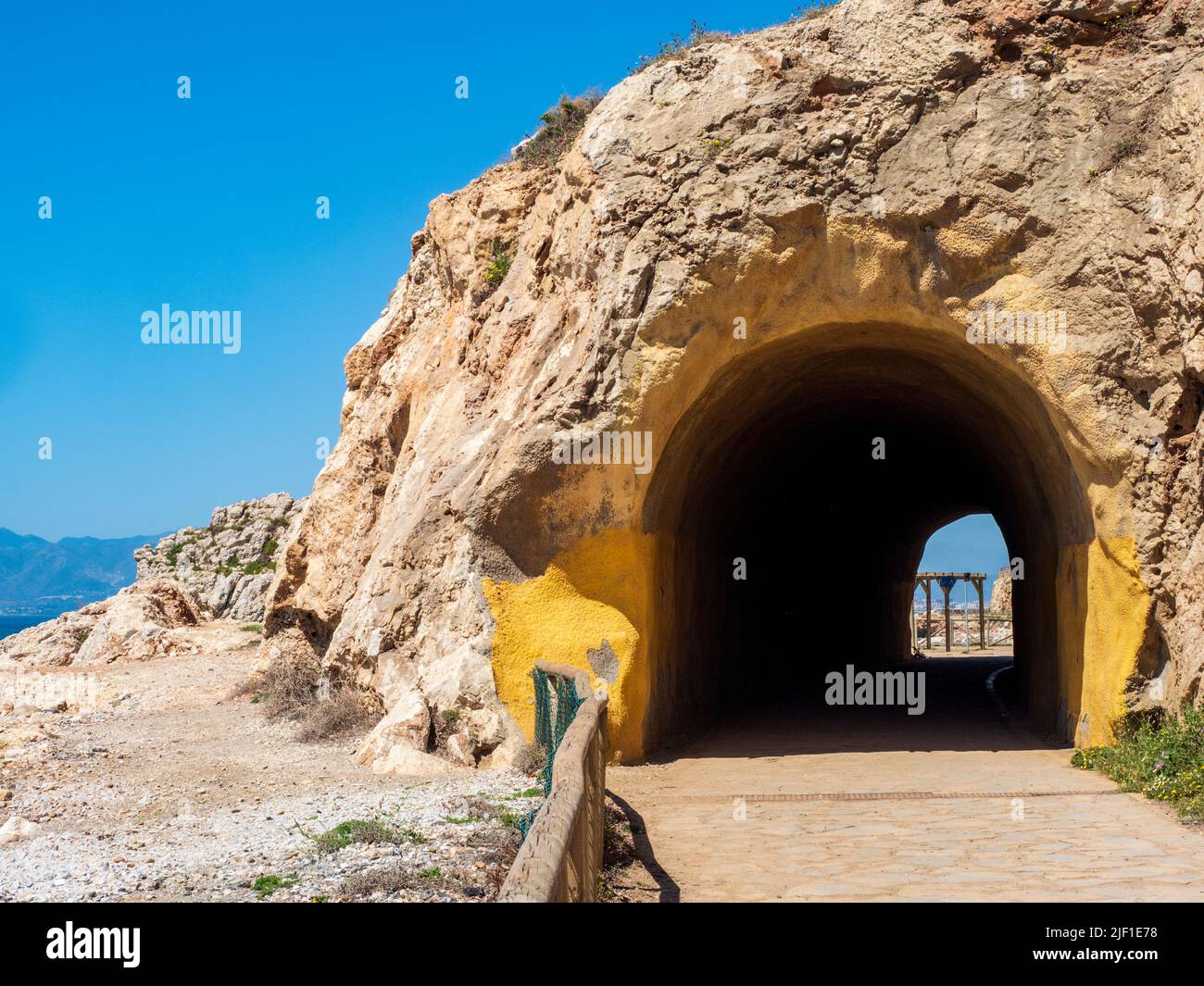 Wanderer und Radfahrer nutzen den Küstenweg entlang der Küste von Malaga, um durch seine Tunnel vor dem Meer Sport zu treiben. Stockfoto