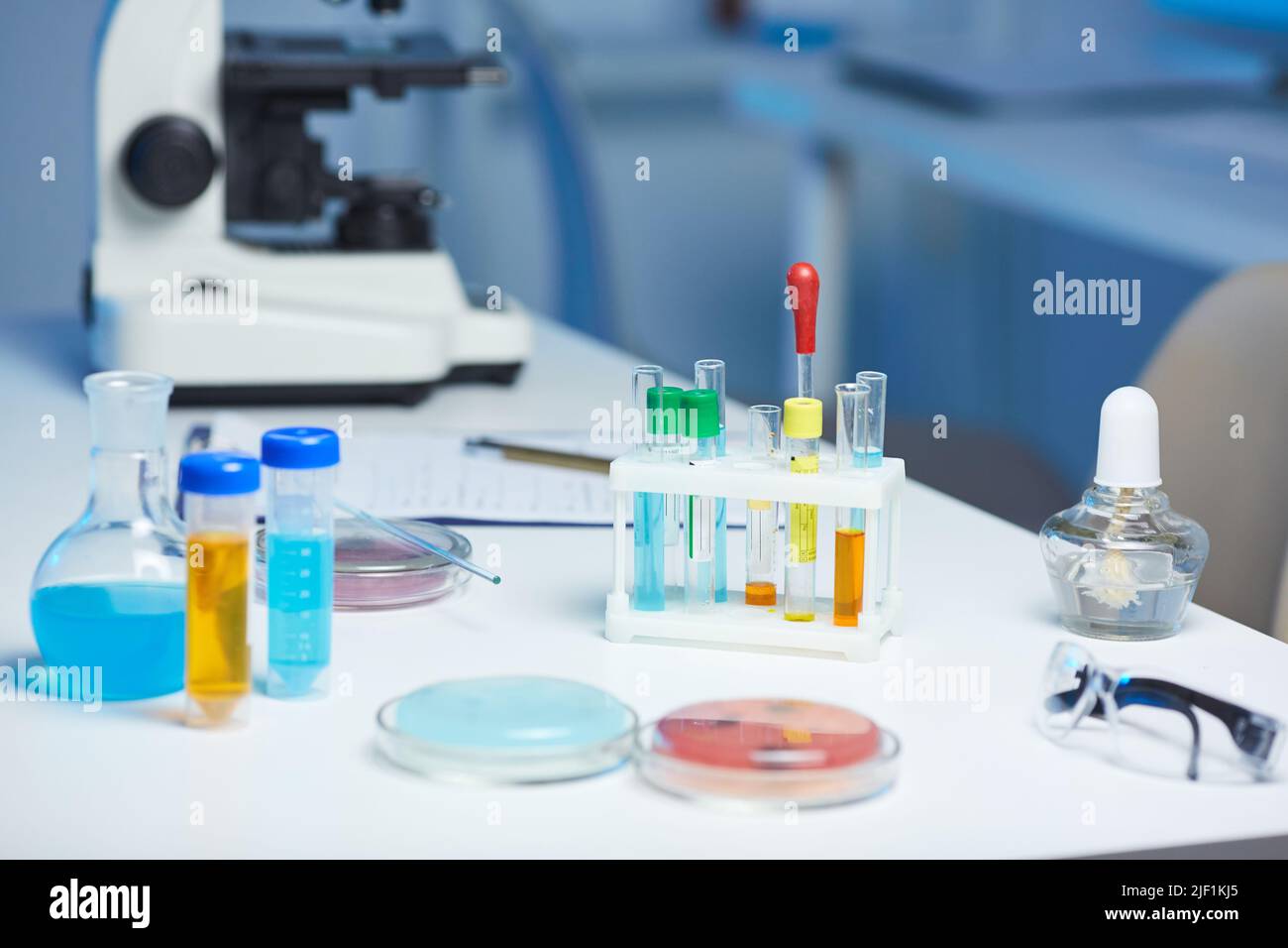 Laborausstattung: Reagenzgläser, Petrischalen, Schutzbrille, Pipette und Papiere auf dem Schreibtisch Stockfoto