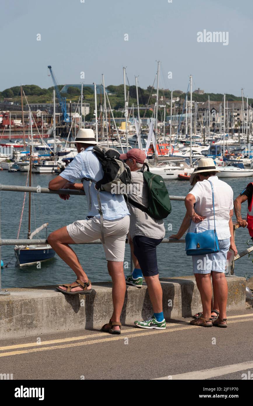 Falmouth, Cornwall, England, Großbritannien. 2022. Urlauber mit gebräunten Beinen beobachten den Hafen von Falmouth Stockfoto