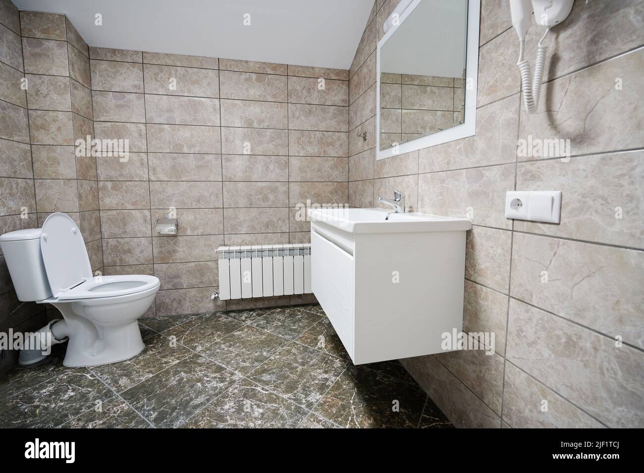 Sauberes Waschbecken mit Spiegel und Toilettensitz Stockfoto