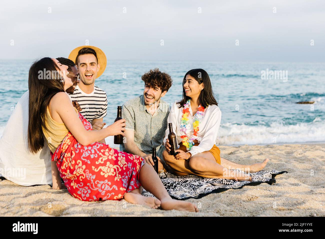 Glückliche multirassische Freunde, die Spaß haben, zusammen mit Getränken am Strand zu jubeln Stockfoto