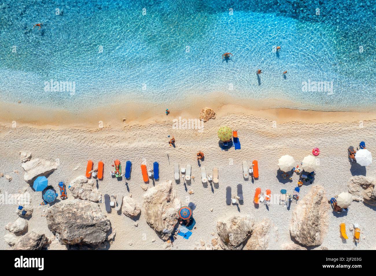 Luftaufnahme des blauen Meeres, Strand mit Sonnenschirmen, Felsen, Wasser Stockfoto