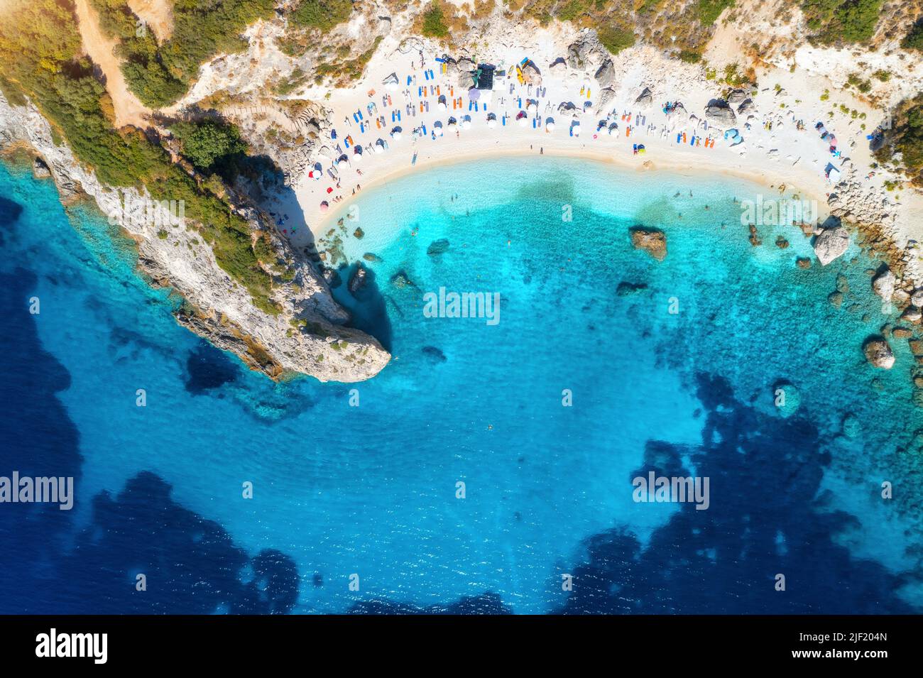 Luftaufnahme des blauen Meeres, Felsen, Sandstrand mit Sonnenschirmen Stockfoto