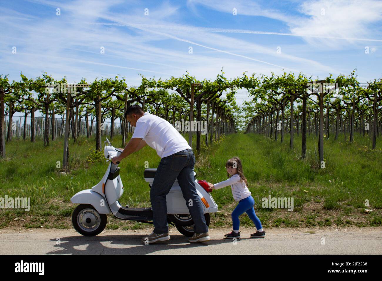 Schönes Bild von einem Vater, der mit seiner Tochter ein Motorrad schiebt, nachdem er zu Fuß zurückgelassen wurde Stockfoto