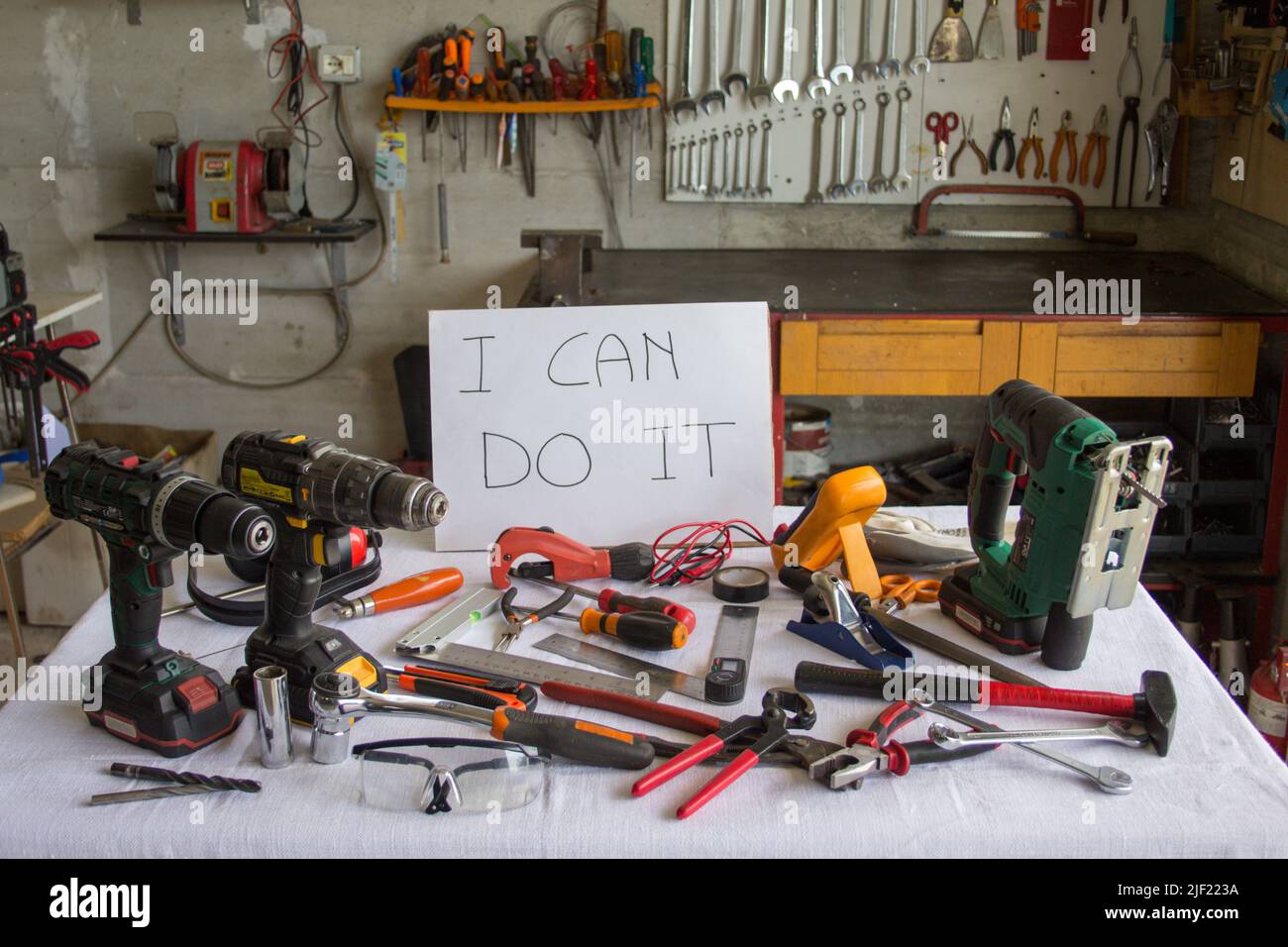 Bild eines Tisches mit verschiedenen Arbeitsmitteln und einem Schild mit der Aufschrift „Ich kann es reparieren“ Stockfoto