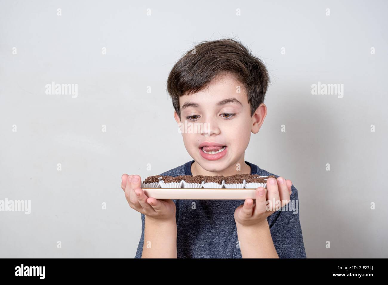 9-Jährige schaut sich ein Tablett mit mehreren brasilianischen Fudge-Kugeln an. Stockfoto