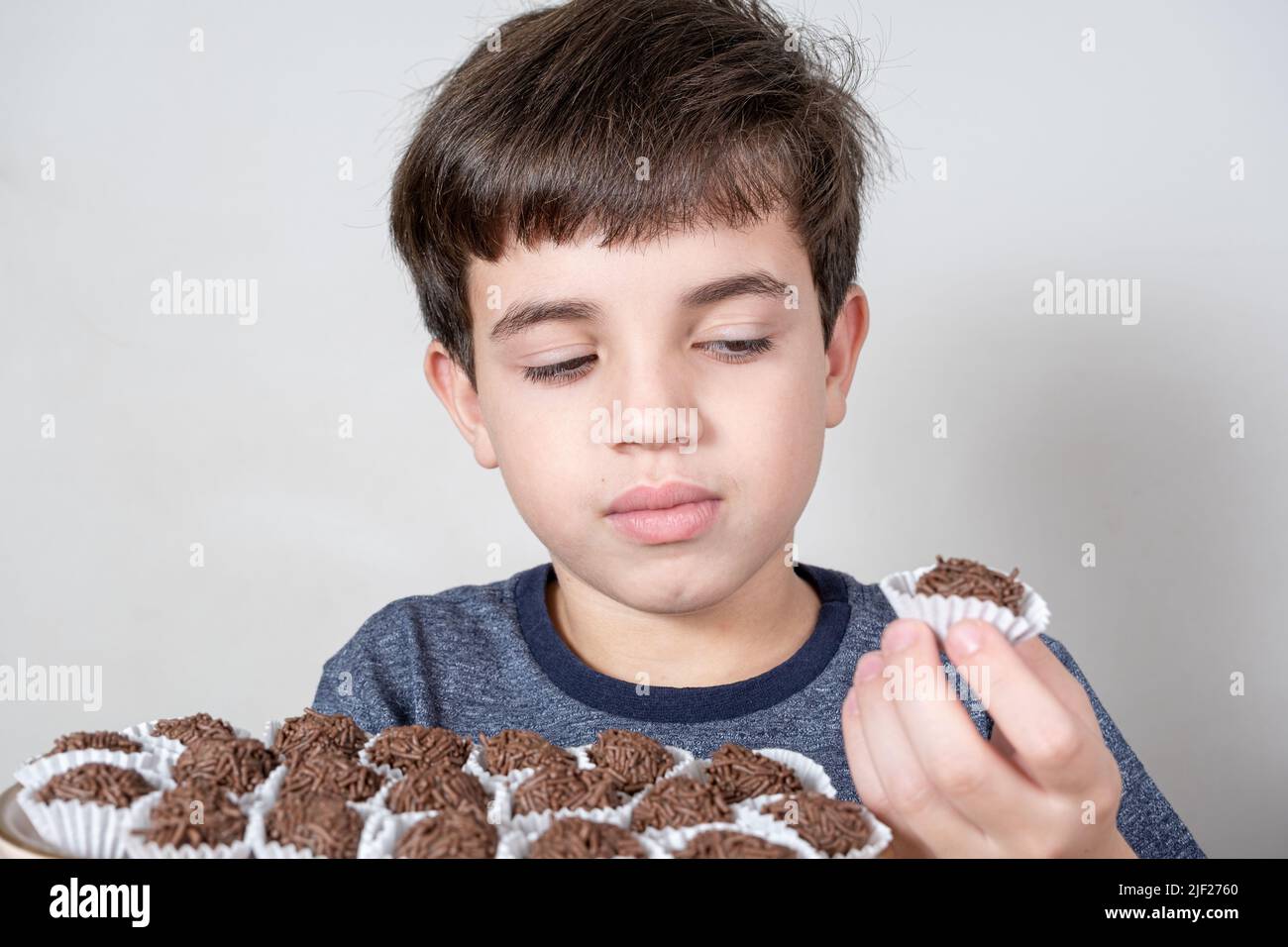 Der 9-jährige Brasilianer schaut arglistig auf einen brasilianischen Fudge Ball. Stockfoto