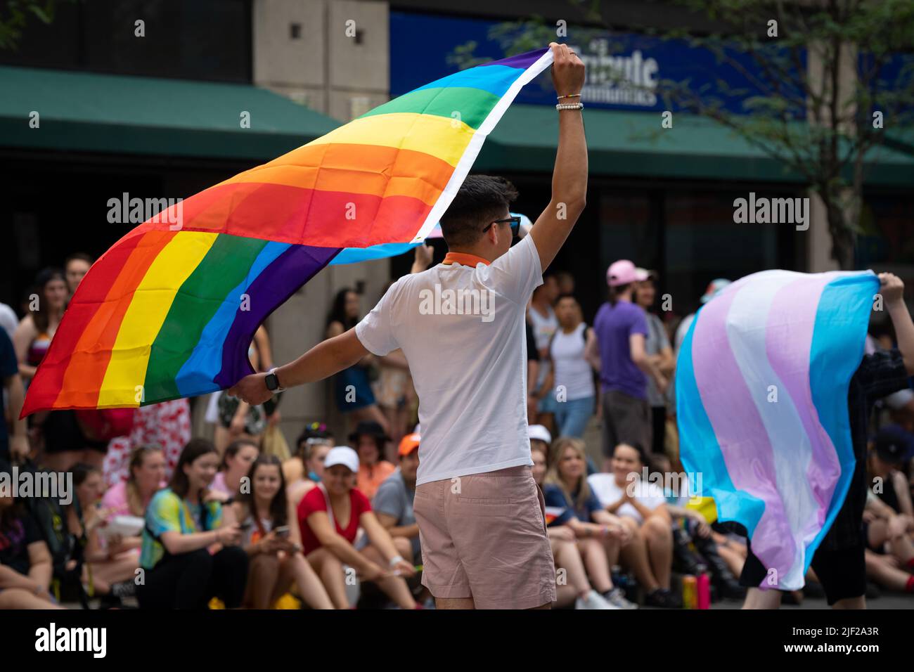 Bei der Toronto Pride Parade 2022 winken Menschen die Regenbogenflagge und eine Trans-Flagge. Stockfoto