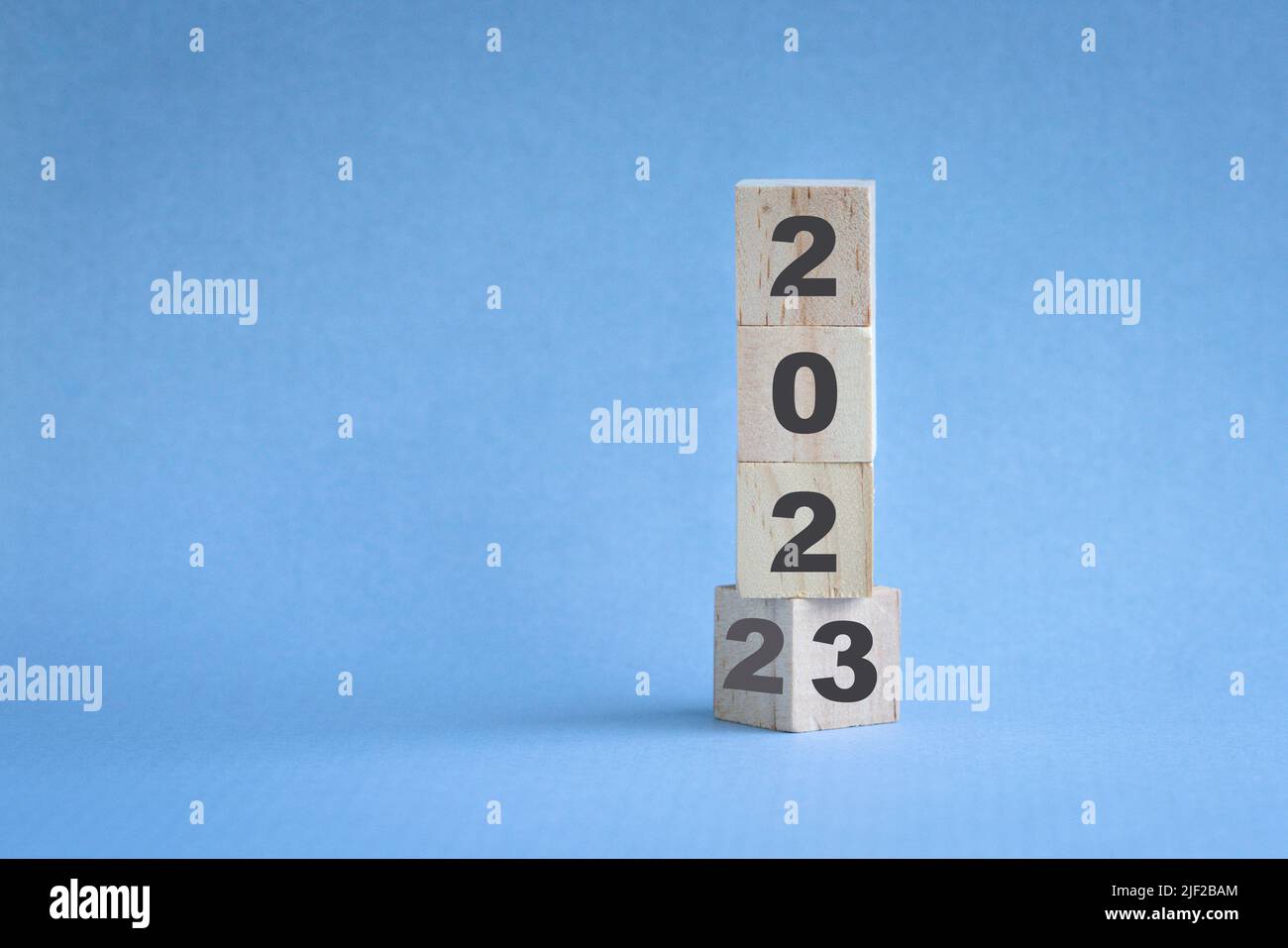 Holzwürfelbestand gestapelt, Änderung von 2022 auf 2023. Blauer Hintergrund, mit Kopierbereich. Stockfoto