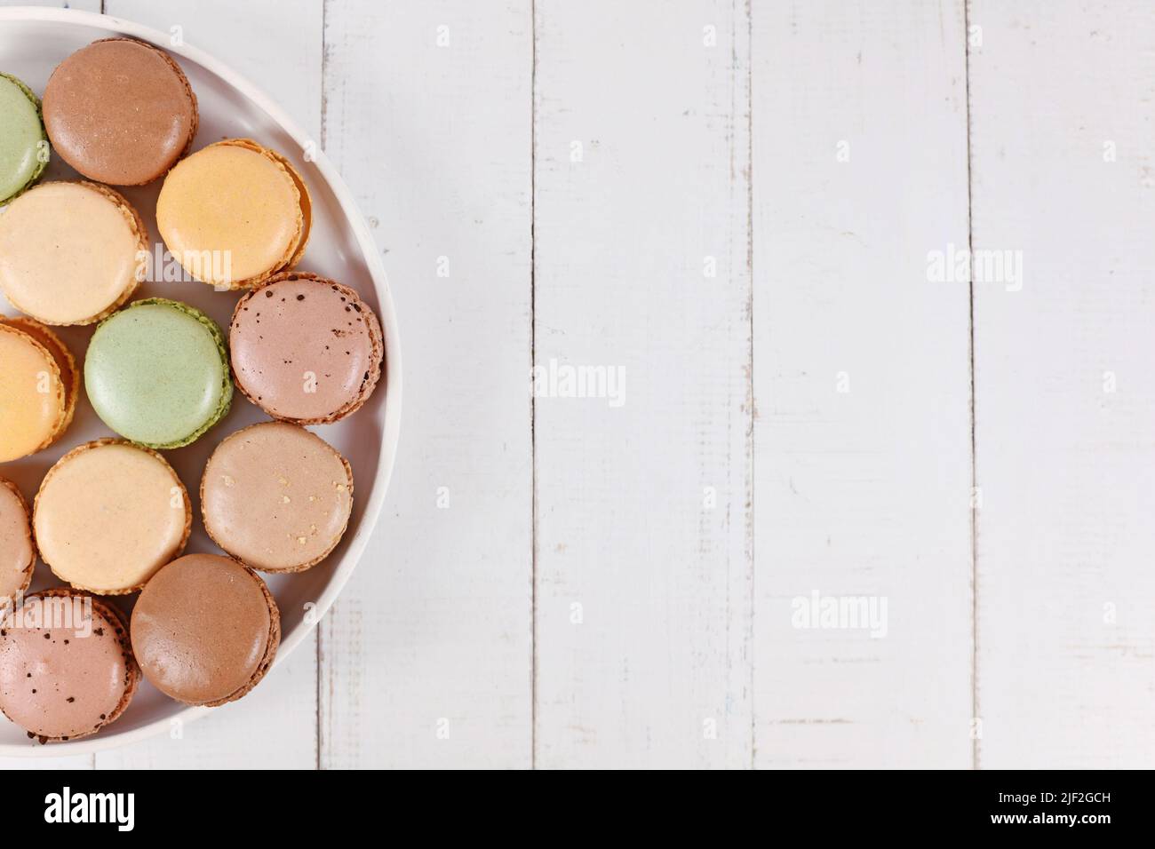 Braune, beige, grüne und cremefarbene französische Macarons auf dem Teller mit Kopierfläche Stockfoto