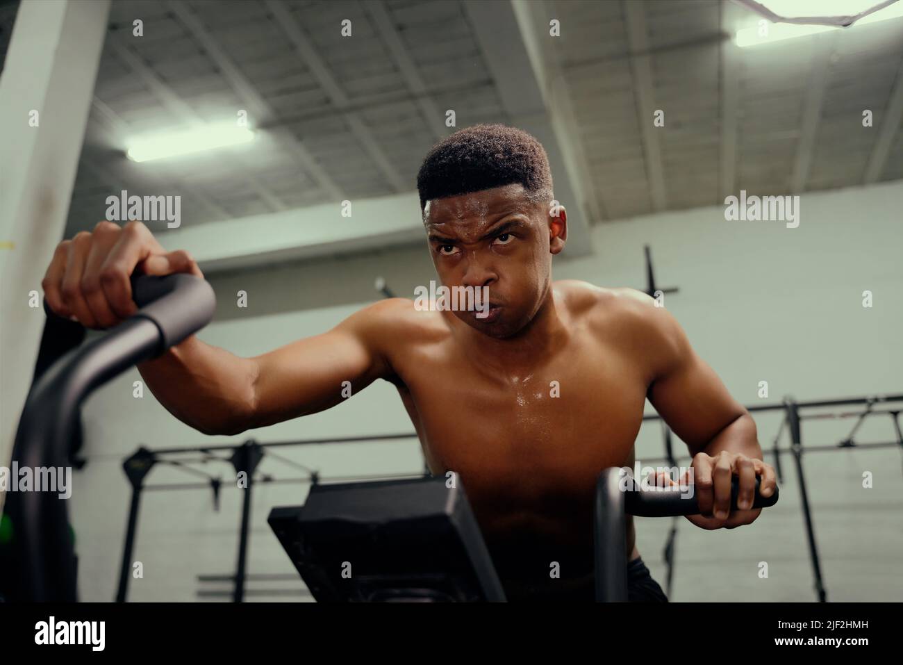 Afroamerikanischer Mann mit einem Crosstrainer beim Cross-Fit-Training. Männlicher Athlet, der intensiv im Fitnessstudio trainiert. Hochwertige Fotos Stockfoto