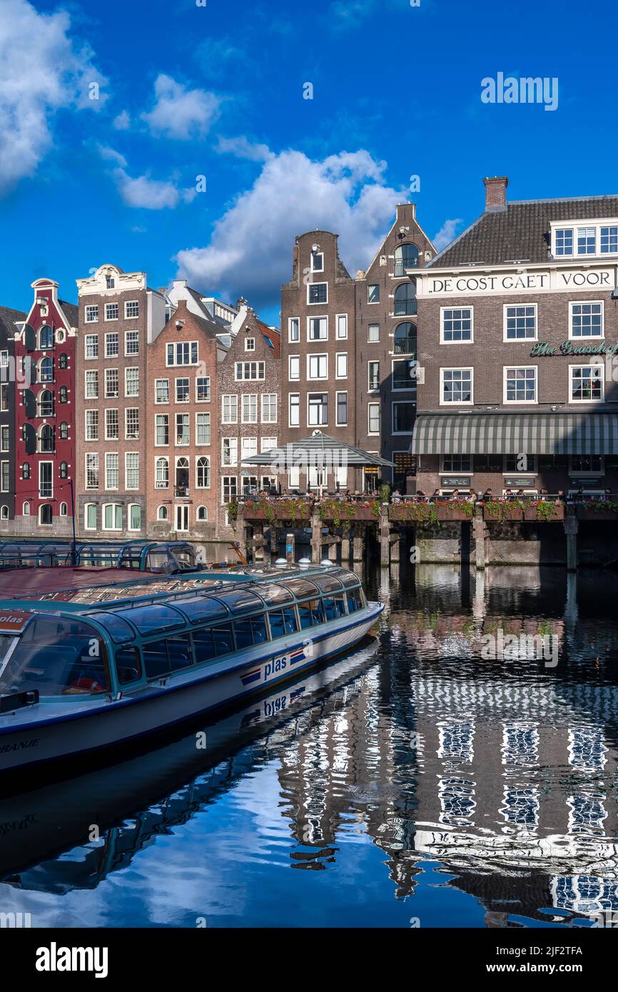 Atemberaubende alte Lagerhäuser, Geschäfte und Apartments an den berühmten Grachten Amsterdams. Aufgenommen an einem sonnigen Sommerabend mit tiefblauem Himmel. Stockfoto