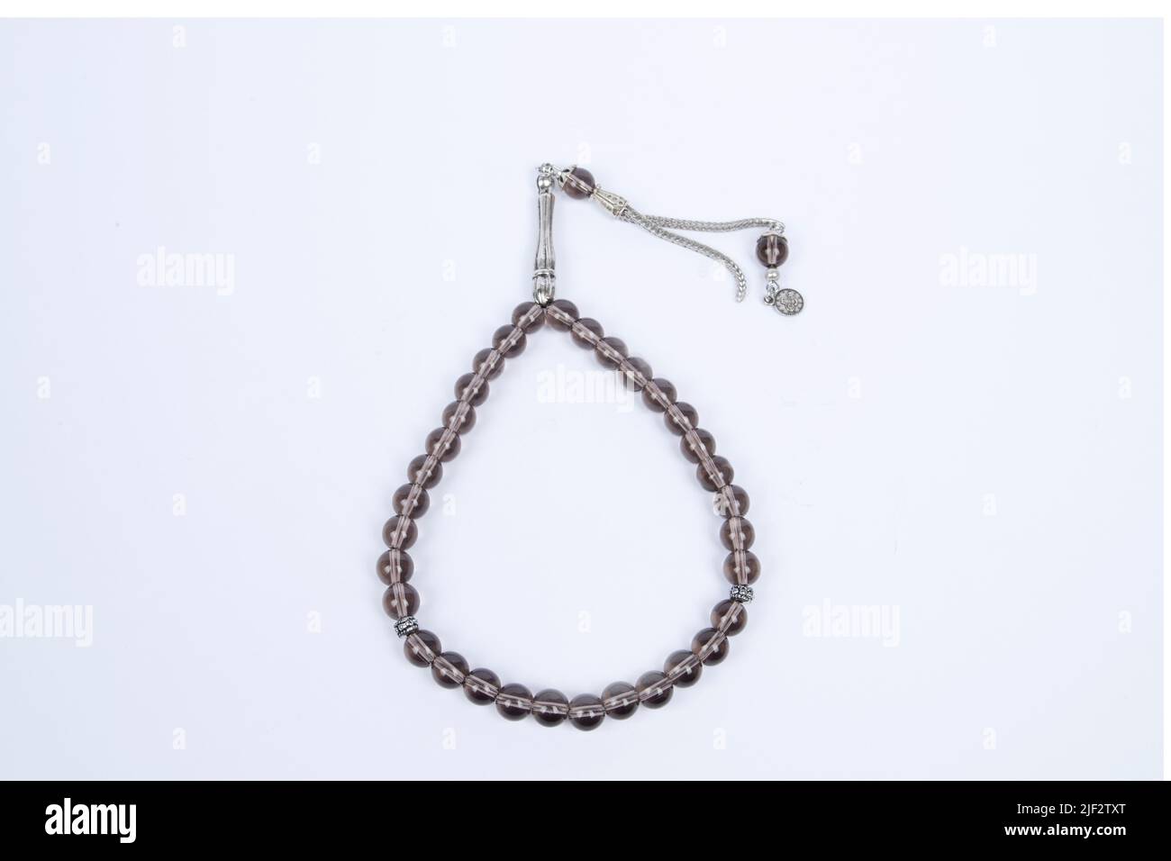 Gebetsperlen mit 33 Knoten aus Stein auf matter Oberfläche auf weißem Grund Stockfoto