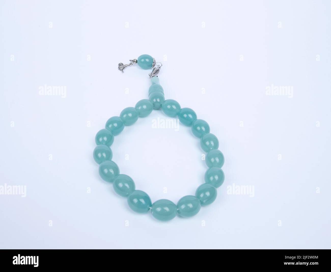Gebetsperlen mit 33 Knoten aus Stein auf matter Oberfläche auf weißem Grund Stockfoto